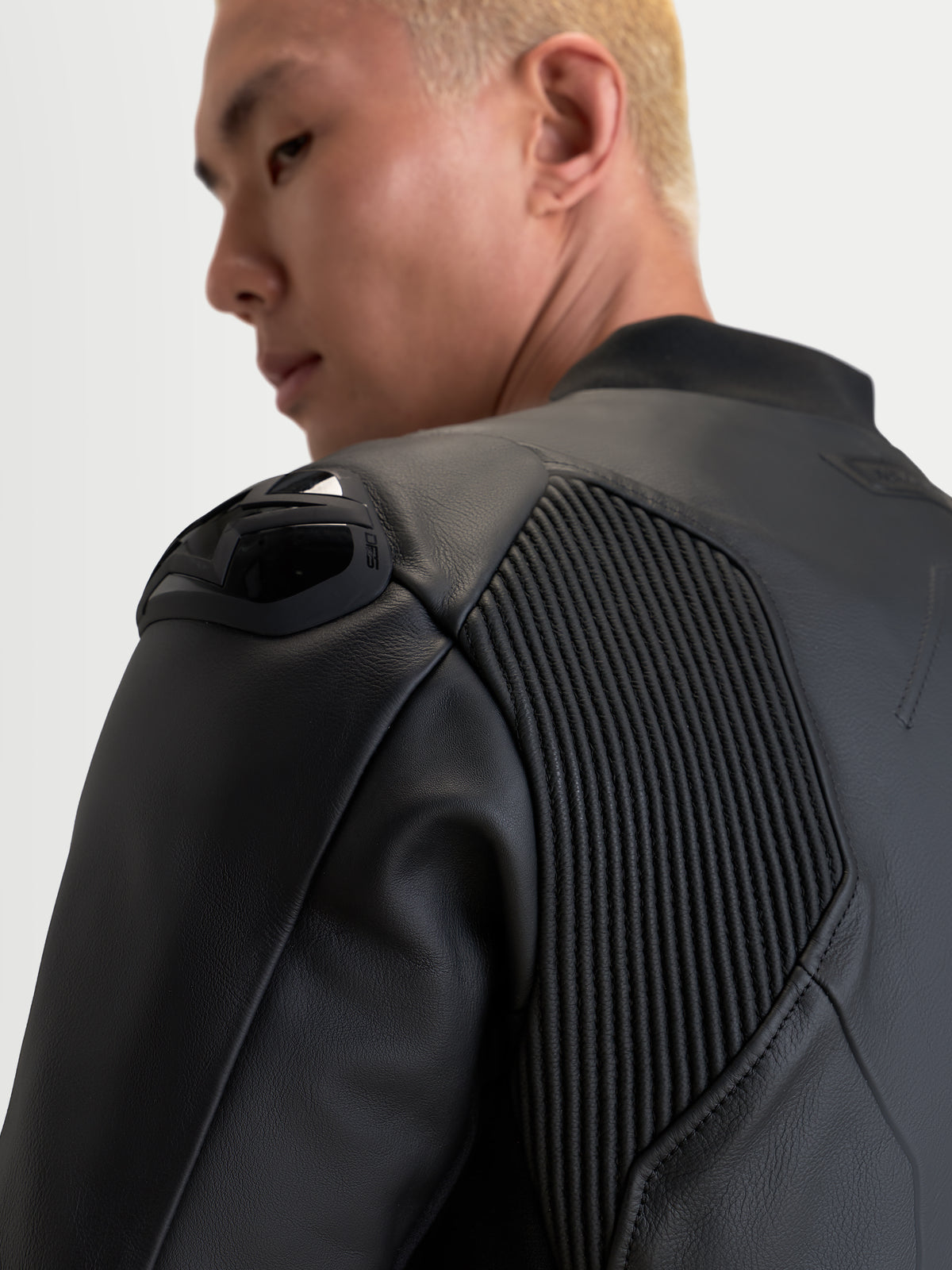 Alpinestars Caliber V2 casaco de couro, preto, vista em pormenor focada na proteção de ombros e painéis de mobilidade em acordeão num motociclista