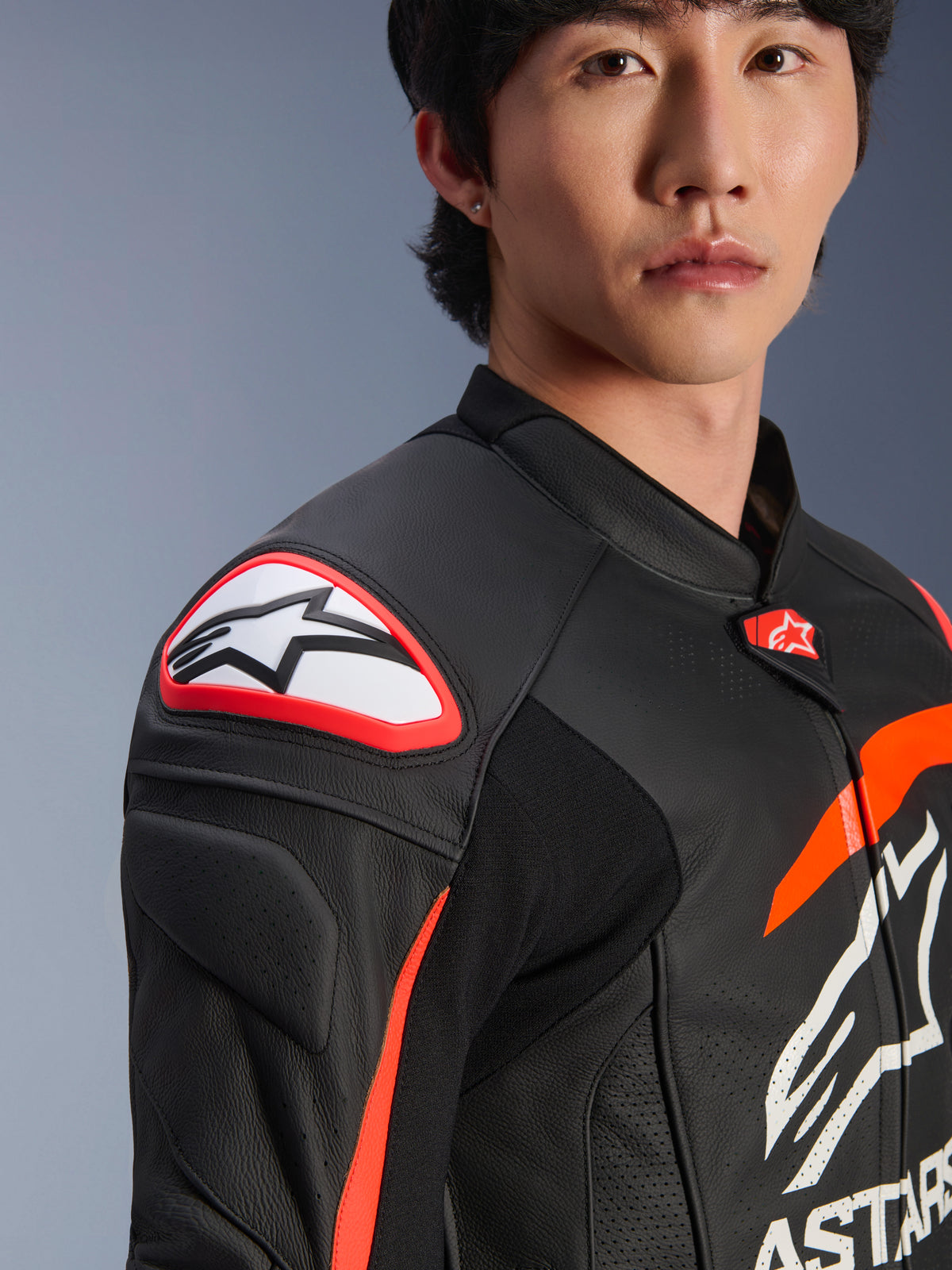 Jaqueta de Couro Alpinestars GP Plus R V4 Airflow, Preto, Vermelho Flúor e Branco, pormenor de modelo a usar a jaqueta, com o logótipo Astar em destaque no slider de ombro e peito em couro perfurado para máximo fluxo de ar, vestuário profissional de desportos motorizados