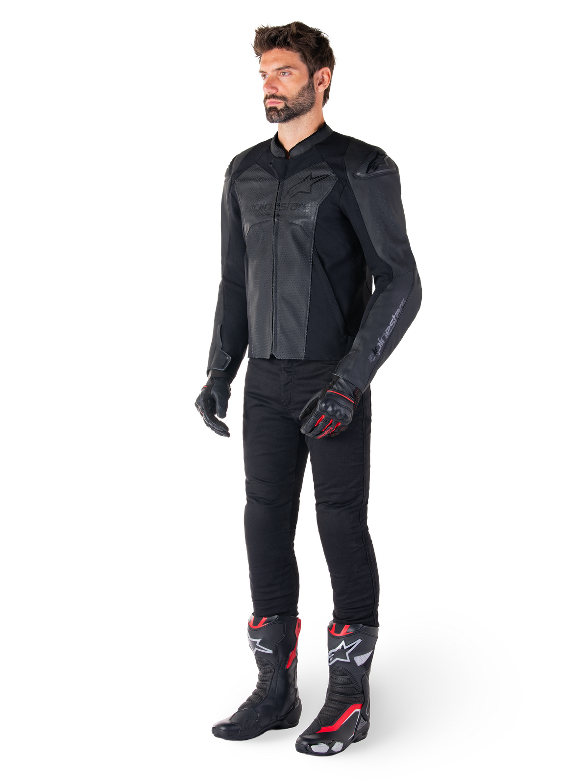 Homem a usar casaco de couro Alpinestars Faster V3 Airflow em preto, combinado com calças pretas, luvas de motociclismo pretas e vermelhas, e botas de corrida pretas com pormenores vermelhos e brancos, equipamento completo de condução desportiva