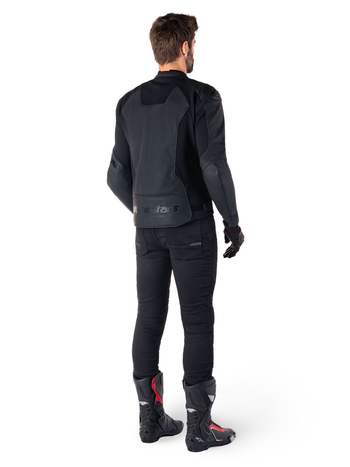 Alpinestars Faster V3 Airflow Leather Jacket, preto, vista traseira de um homem a usar um casaco de pele desportivo com painéis perfurados nas costas e o logótipo Alpinestars, combinado com calças de motociclismo pretas e botas pretas e vermelhas.