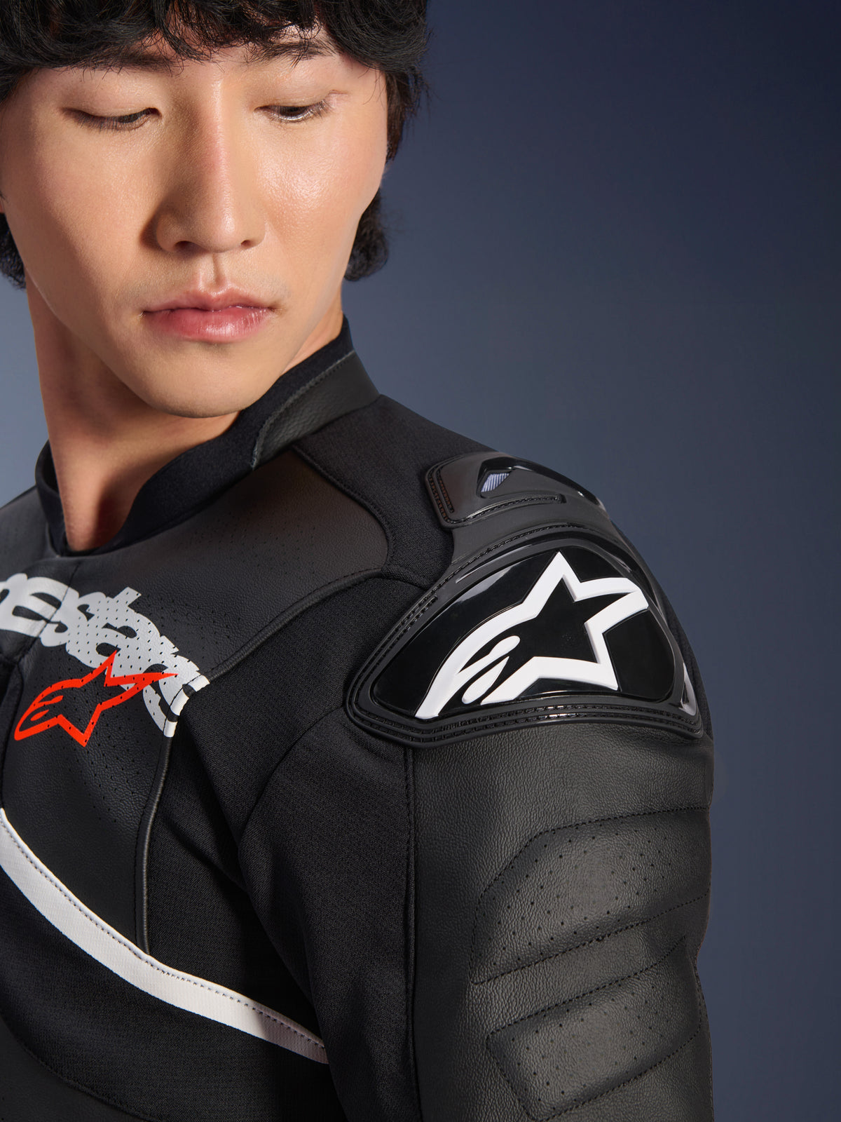 Detalhe da Jaqueta de Couro Alpinestars Atem V5 em preto e branco, com o protetor de ombro DFS RR com logótipo de estrela branco, construção em couro perfurado e gráficos no peito inspirados em corridas