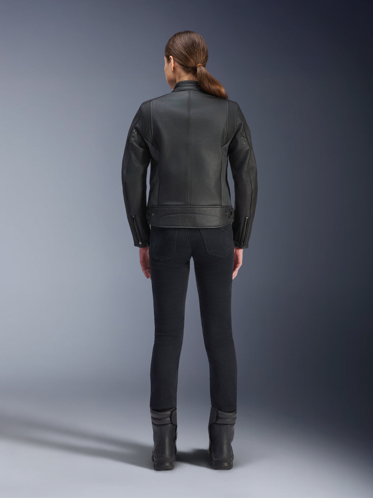 Jaqueta Stella Dyno Leather da Alpinestars, jaqueta de motociclismo feminina, preta, vista traseira que realça a construção em couro bovino com corte ajustado, design heritage minimalista, usada com calças e botas pretas para um visual de motociclismo urbano