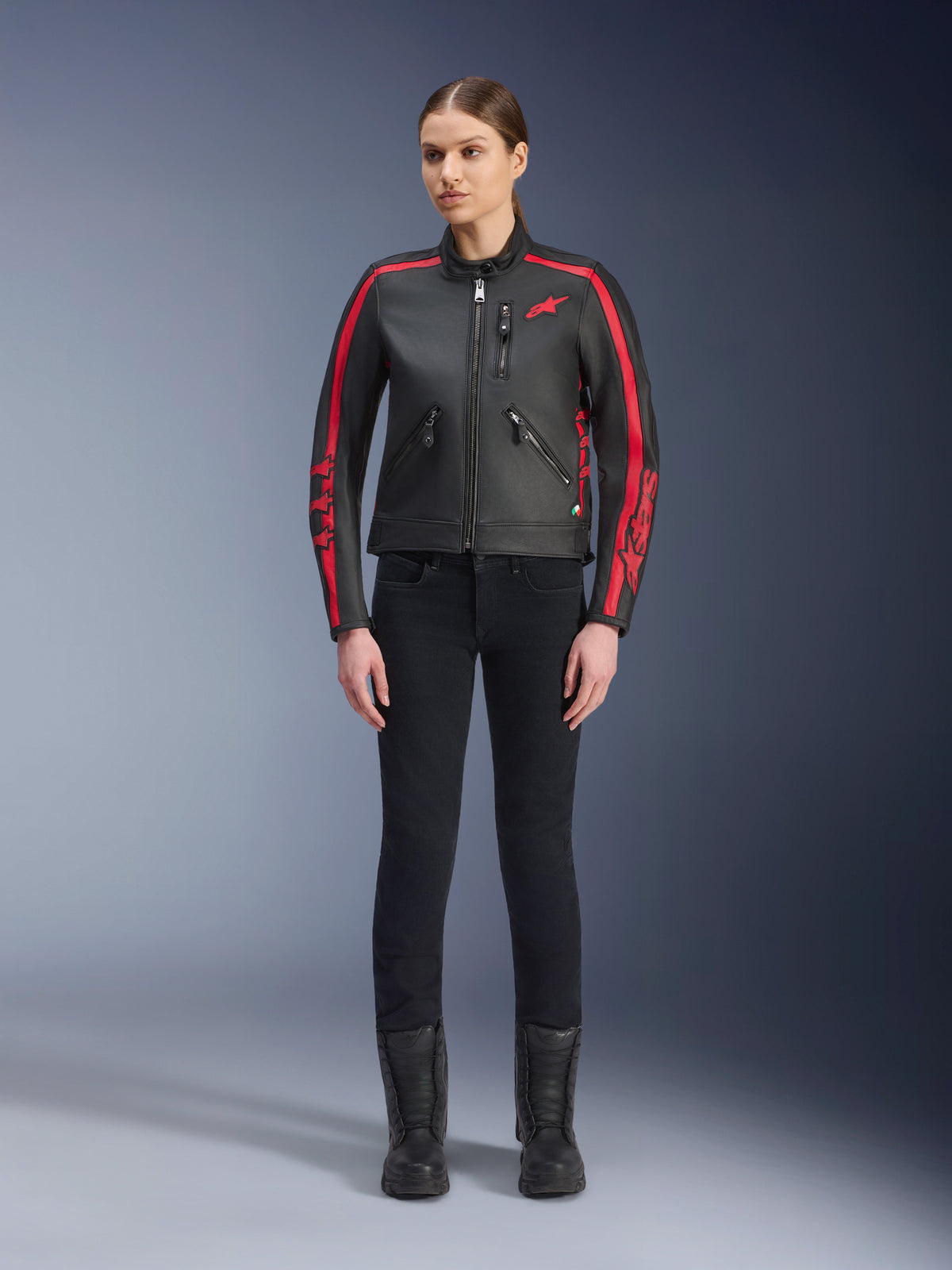 Casaco de Pele Alpinestars Stella Dyno, casaco de motociclismo para mulher, preto e vermelho Haute Red, com riscas de corrida vermelhas nos ombros e mangas, logótipo de estrela vermelha no peito, usado com calças pretas de corte justo e botas, pele bovina premium com um design heritage moderno