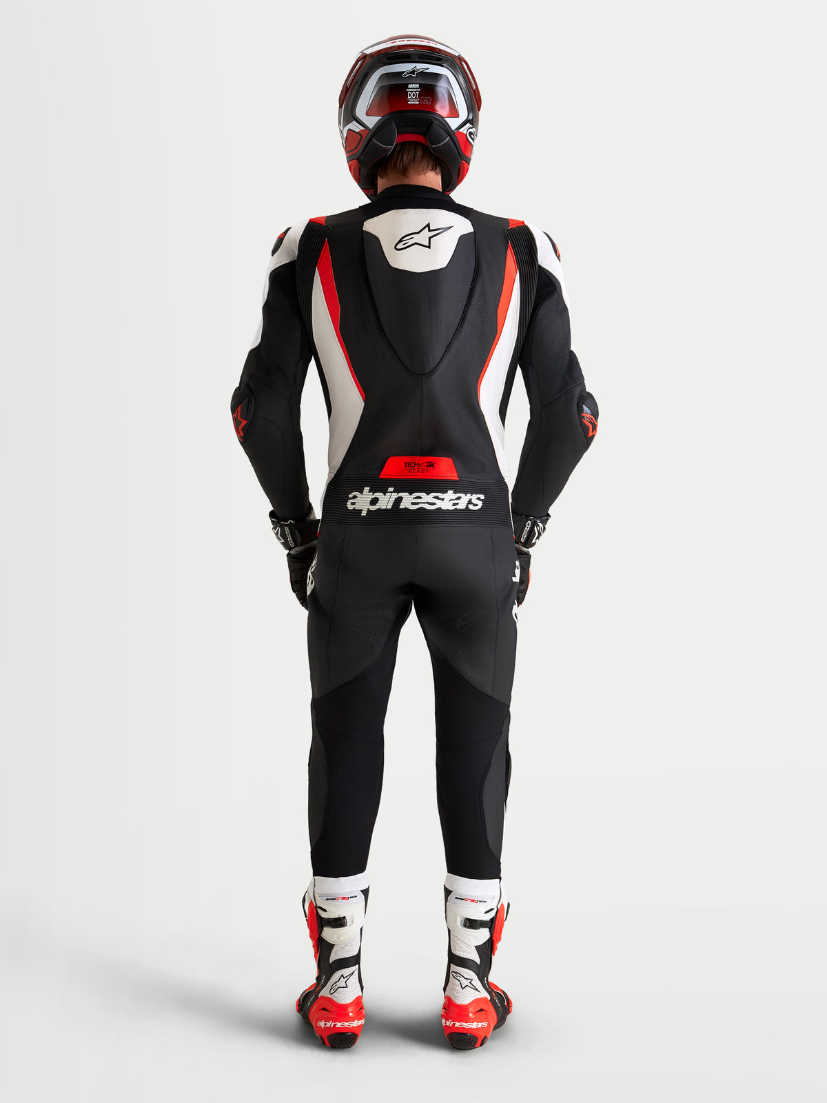 Alpinestars Missile V3 Leather Suit 1 Pc, Motorcycle Racing Suit, Men's, Black White Red Fluo, featuring AAA-rated leather construction, aerodynamic speed hump, and Alpinestars branding, rear view of a rider wearing the suit and helmet