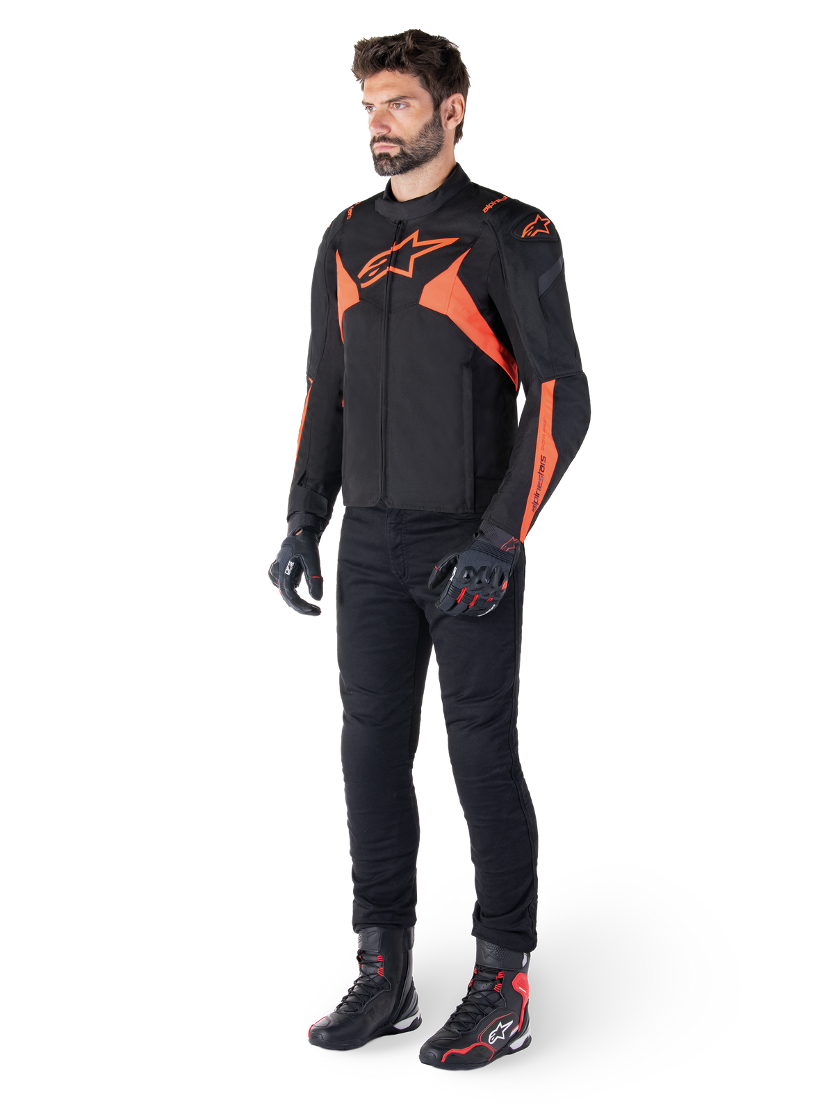 Casaco Alpinestars T-Jaws V4 Waterproof, preto e vermelho fluo, usado por um modelo masculino com calças, luvas e botas pretas, apresentando detalhes em laranja vibrante e o logótipo Alpinestars, design desportivo para motociclismo