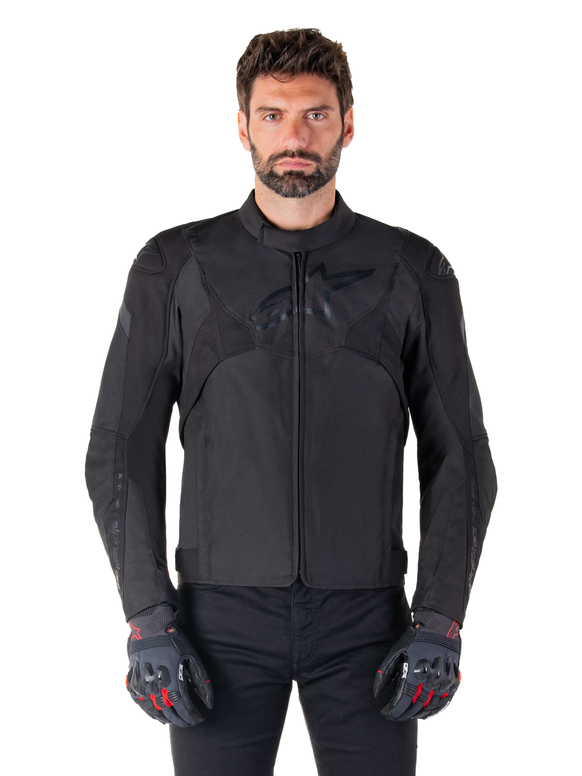 Alpinestars T-Jaws V4 Waterproof Jacket, casaco de motociclismo desportivo preto, usado por um homem com luvas pretas com detalhes vermelhos, ombros e braços reforçados, design elegante com logótipo discreto no peito, equipamento têxtil para todas as condições climatéricas