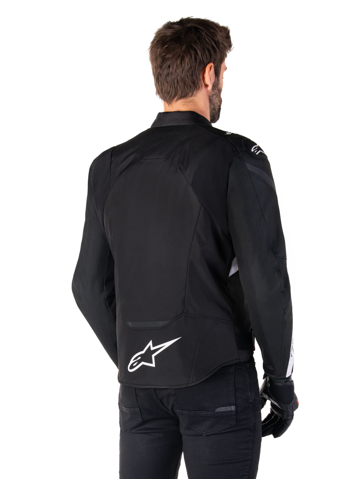 Casaco Impermeável Alpinestars T-Jaws V4, preto e branco, vista traseira, casaco têxtil desportivo de motociclismo com logótipo branco na parte inferior das costas, usado com luvas e calças pretas, apresentando uma silhueta de corte desportivo revisto