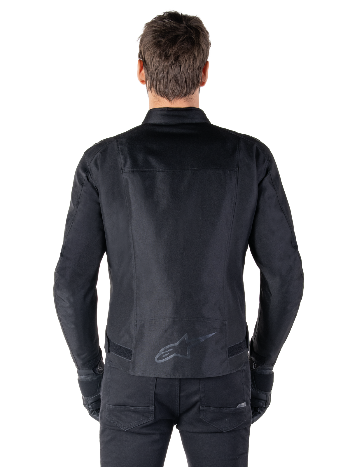 Casaco Alpinestars T-SPS V2 Waterproof, preto, vista traseira mostrando a silhueta de corte desportivo, logótipo Alpinestars refletor na parte inferior das costas e costas alongadas para maior cobertura durante a condução.
