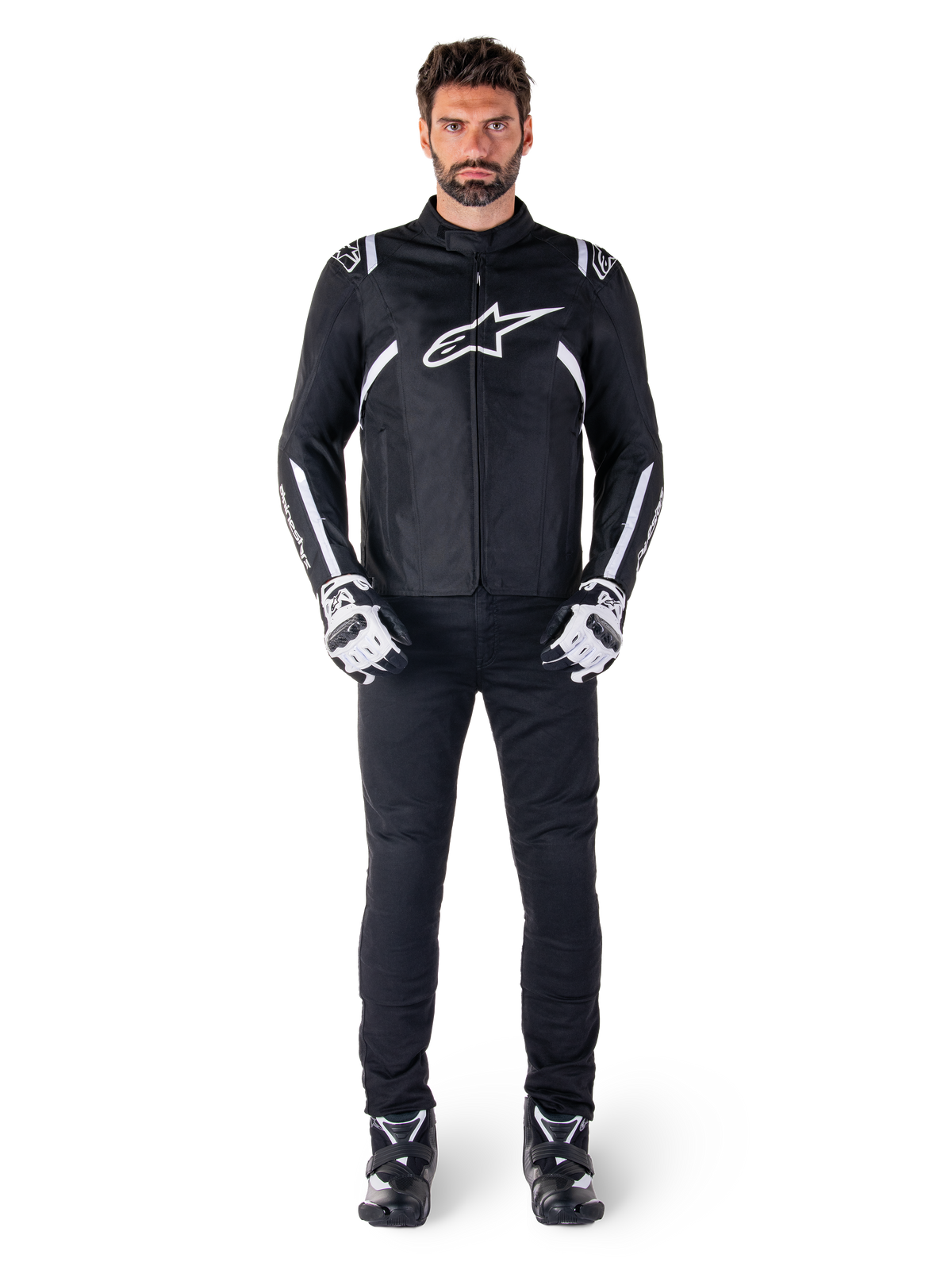Casaco Alpinestars T-SPS V2 Waterproof, preto e branco, vestido por modelo masculino com calças pretas e luvas a condizer, com logótipo Alpinestars branco no peito e detalhes nas mangas, silhueta de corte desportivo para condução de motociclismo em todas as condições meteorológicas