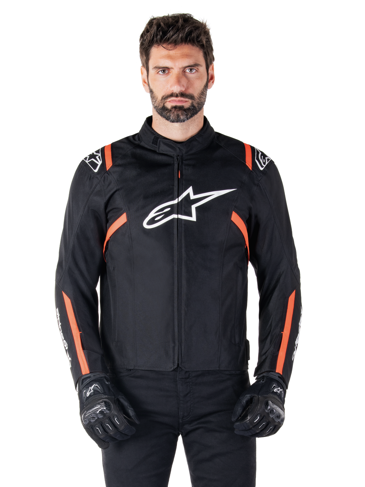 Casaco Impermeável Alpinestars T-SPS V2, preto, branco e vermelho fluo, vestido por um modelo masculino com luvas de motociclismo pretas, com logótipo Alpinestars branco no peito e detalhes em laranja vibrante nos ombros e mangas.