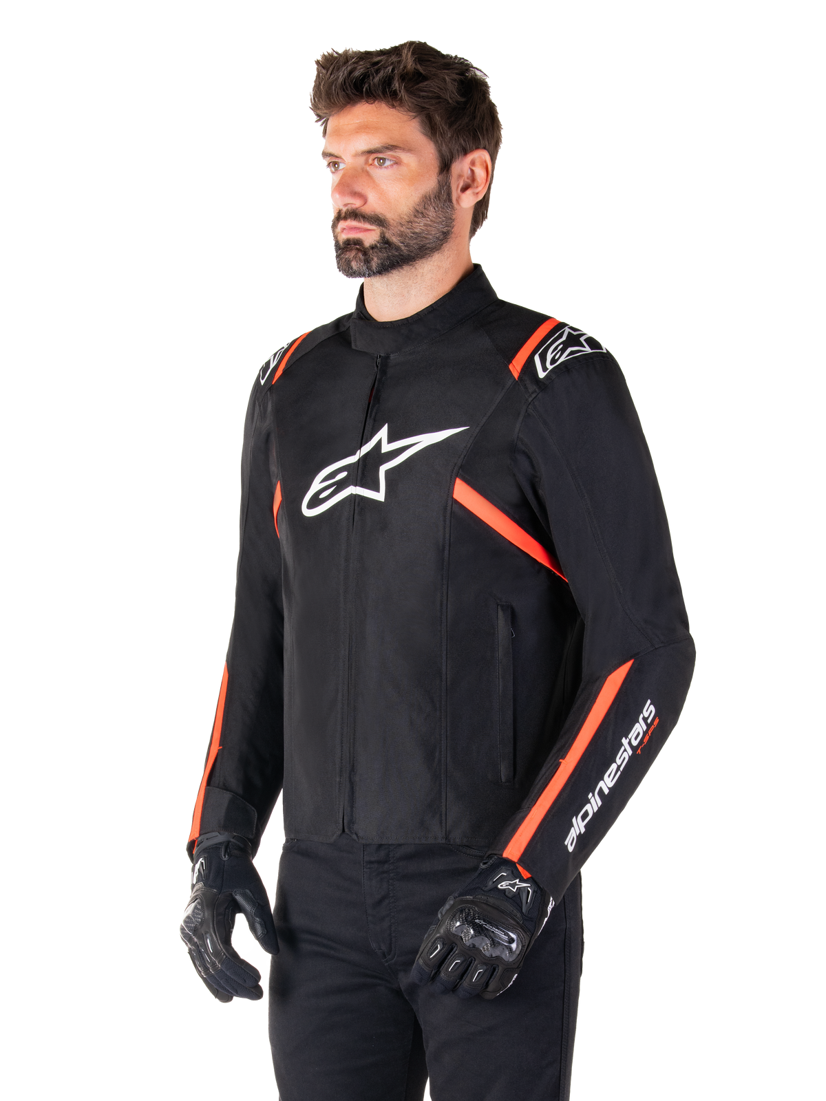 Casaco Alpinestars T-SPS V2 Waterproof, preto, branco e vermelho fluo, vestido por um modelo masculino com luvas e calças pretas, com logótipo Alpinestars branco no peito e detalhes em vermelho fluorescente nos ombros e mangas, design têxtil desportivo