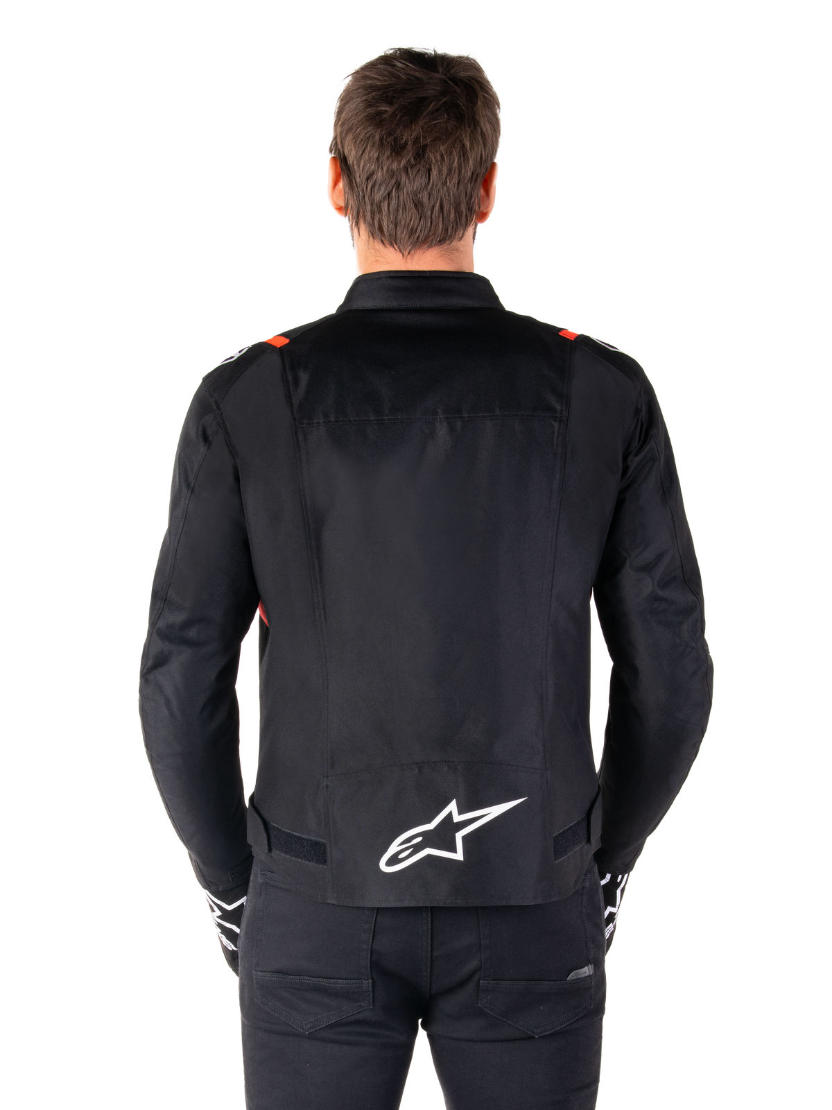 Casaco Alpinestars T-SPS V2 Waterproof, preto com detalhes em branco e vermelho flúor, vista traseira com um grande logótipo Alpinestars branco na zona inferior das costas, casaco de motociclismo têxtil com corte desportivo, usado com calças e luvas pretas