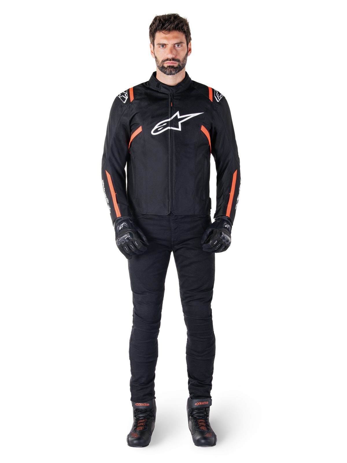 Modelo masculino a usar o casaco Alpinestars T-SPS V2 Waterproof em preto, branco e vermelho fluo, combinado com calças e luvas de motociclismo pretas, com o logótipo Alpinestars branco no peito e detalhes vermelhos nas mangas.