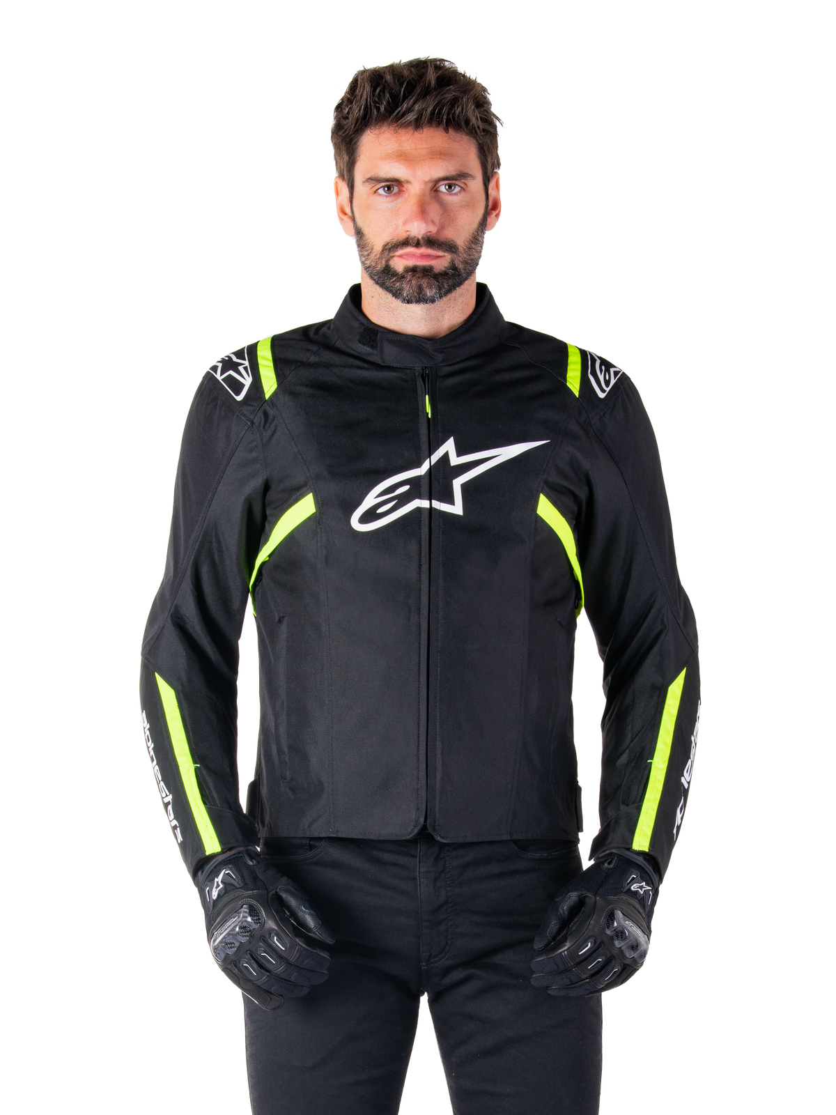 Casaco Impermeável Alpinestars T-SPS V2, casaco de motociclismo, preto com detalhes em branco e amarelo fluorescente, usado por um modelo com luvas pretas, com um logótipo de estrela branco no peito e riscas amarelo néon nas mangas e ombros, equipamento têxtil de estilo desportivo para todas as condições meteorológicas
