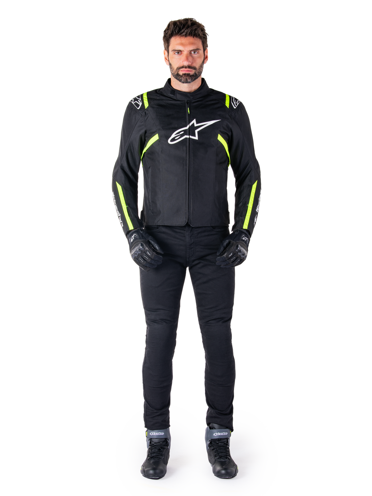 Casaco Alpinestars T-SPS V2 Waterproof, Preto, Branco e Amarelo Fluo, usado por um modelo com calças e luvas de condução pretas, com o logótipo Alpinestars branco no peito e detalhes fluorescentes nos ombros e mangas, equipamento de motociclismo de corte desportivo
