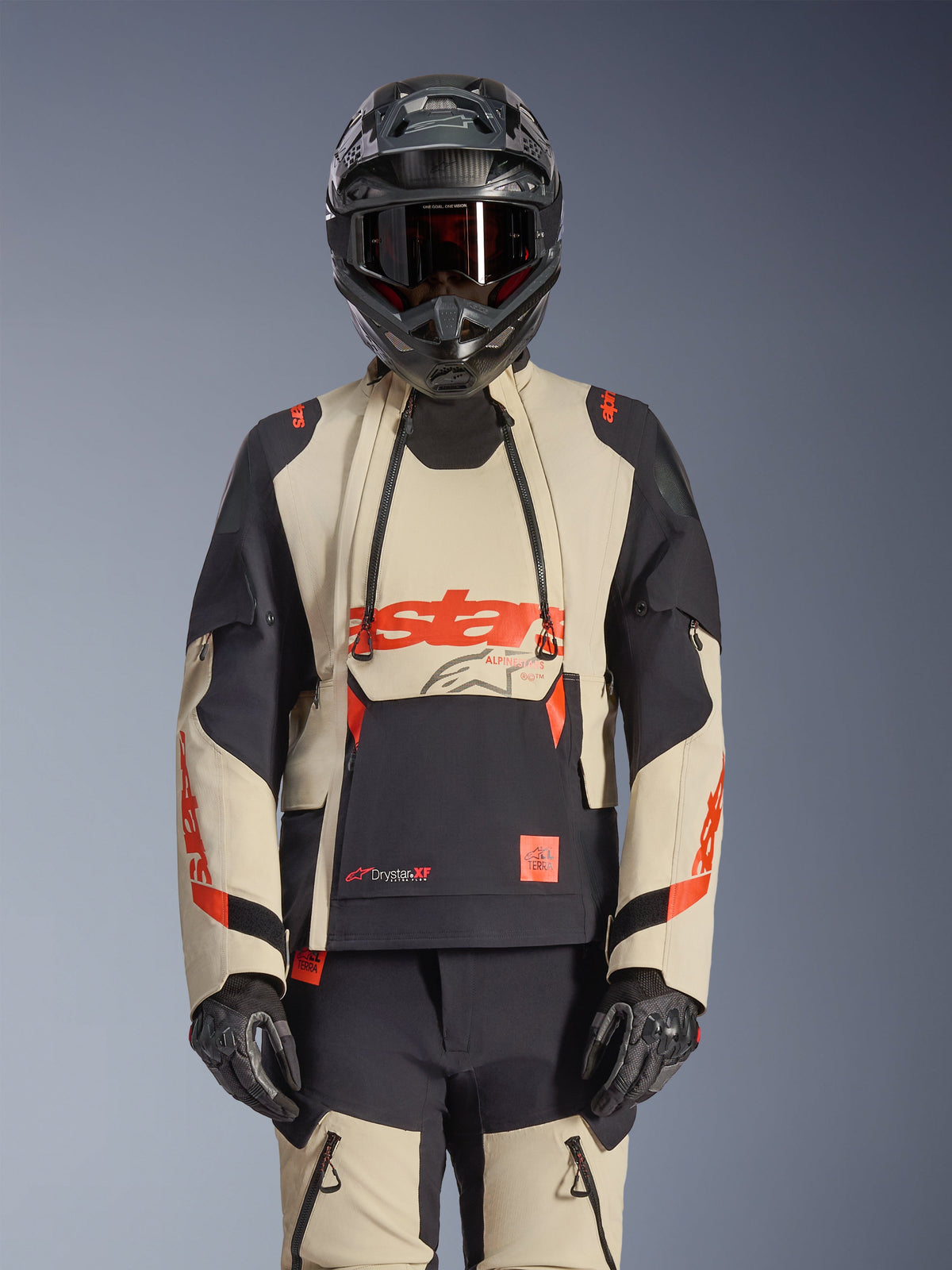Alpinestars Halo Pro Drystar XF Laminated Jacket, casaco de aventura para motociclismo em Mastic Black e bege com detalhes vermelhos, usado com equipamento de proteção completo incluindo capacete e luvas, com painéis de ventilação modulares e construção laminada 3L.