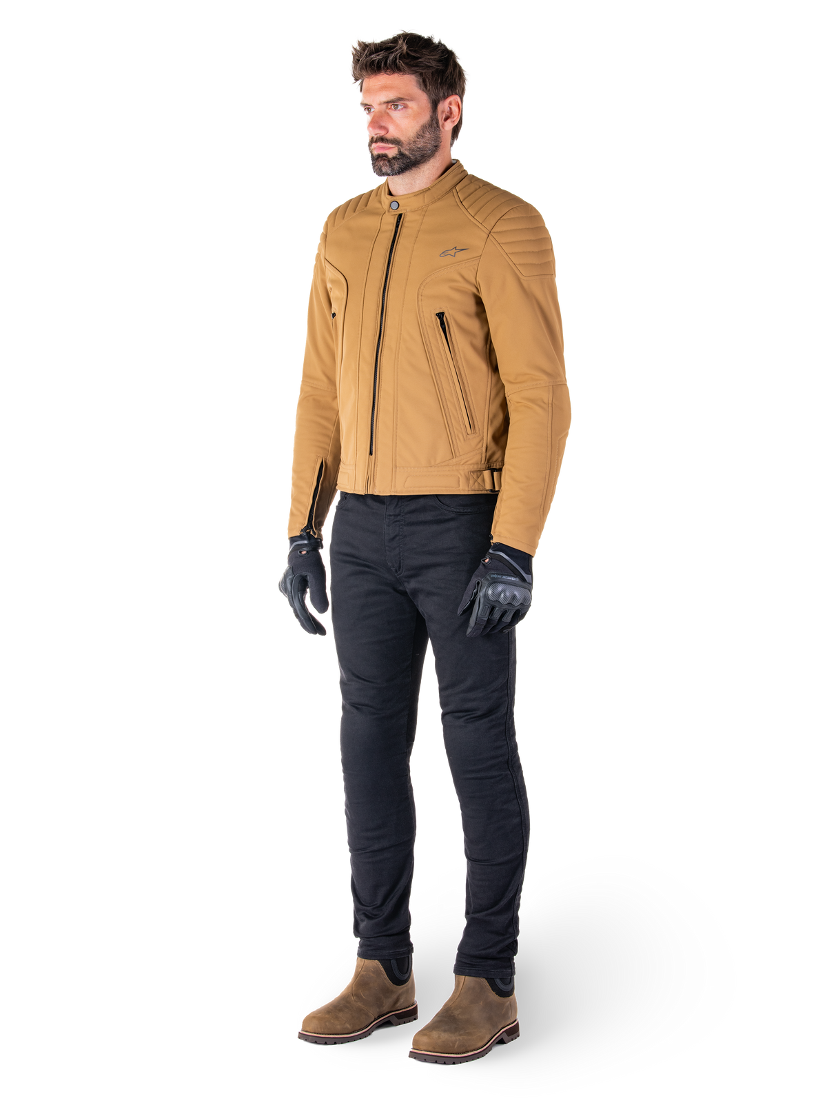 Motociclista a usar o casaco Alpinestars Clayton WR em Utility Brown Light Gold, casaco de motociclista urbano contemporâneo com detalhes acolchoados nos ombros, conjugado com calças pretas, luvas pretas e botas castanhas