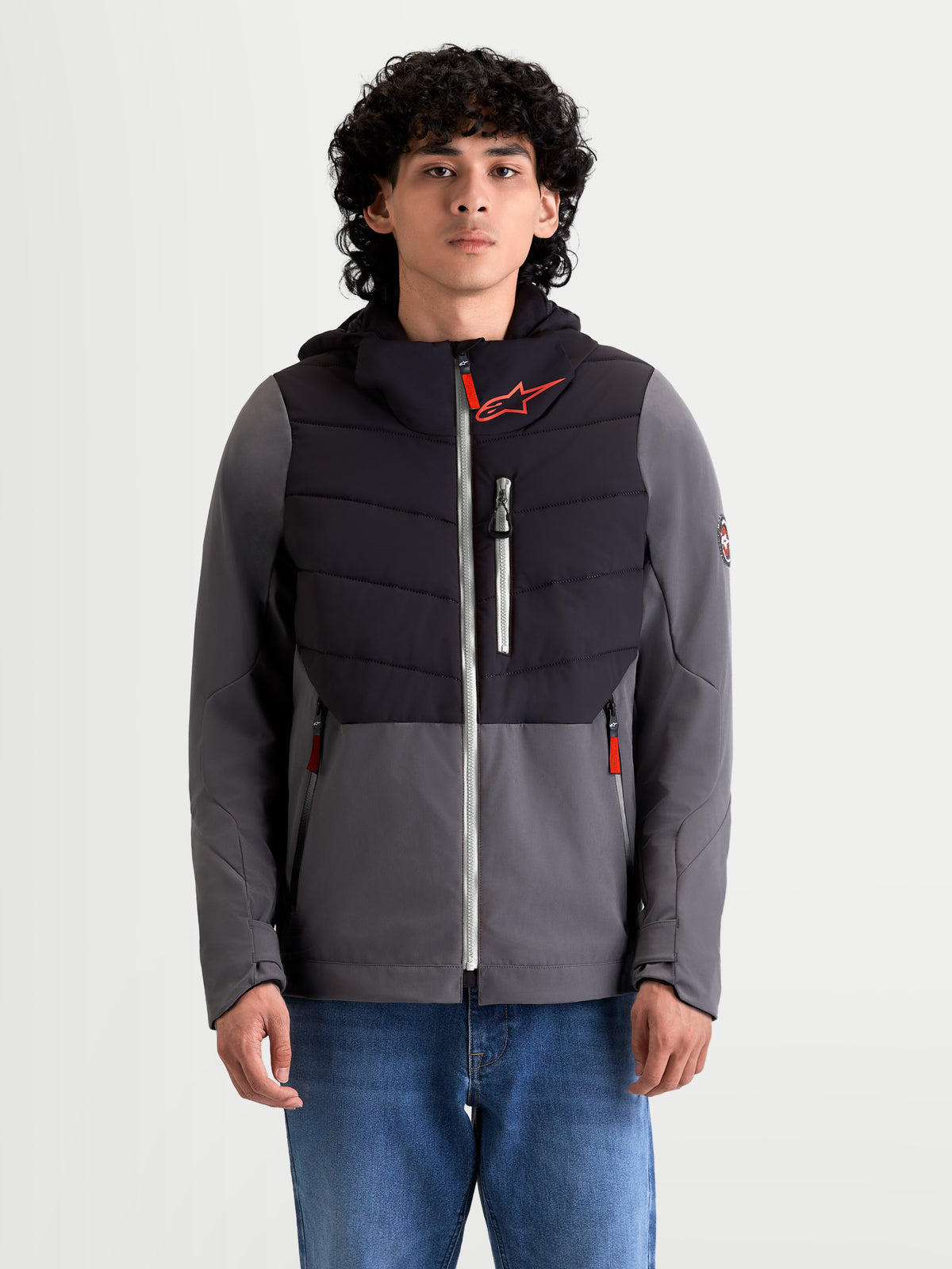 Alpinestars Casaco Therma-Tech Impermeável, casaco de moto urbano têxtil para homem, preto e cinzento escuro, vista frontal num modelo a usar calças de ganga, com construção acolchoada, membrana impermeável e capuz integrado