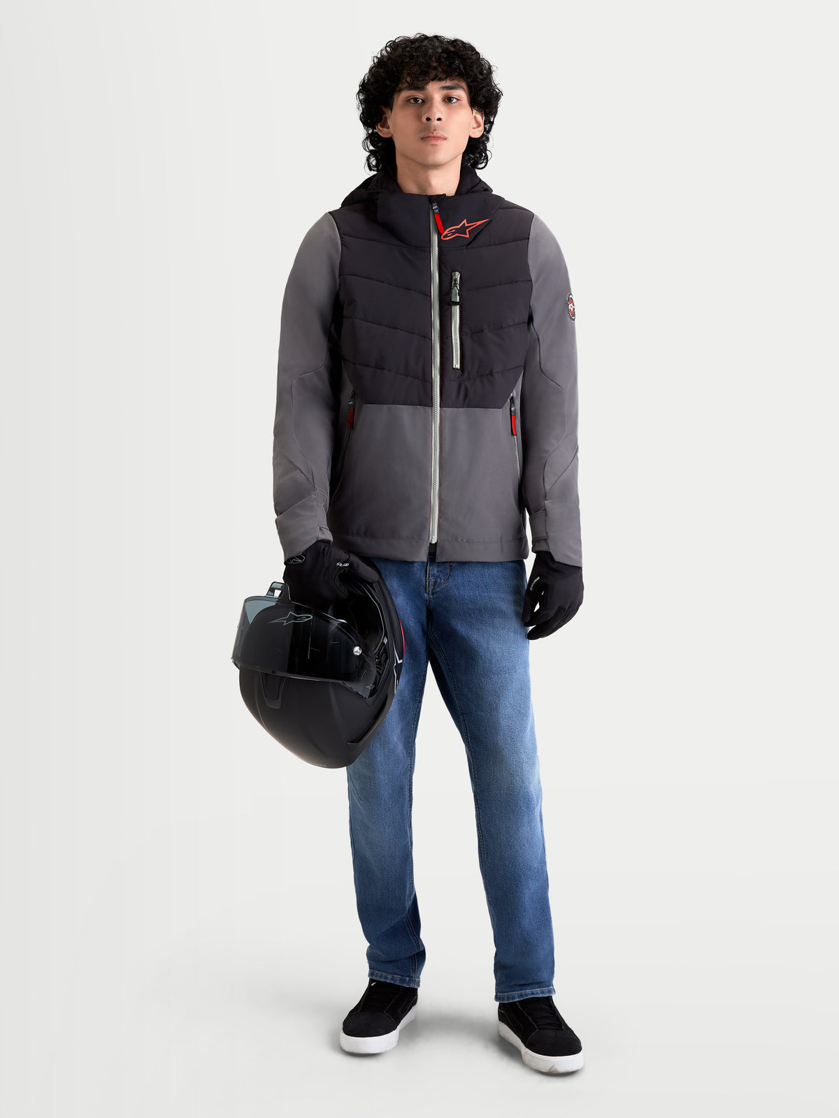 Casaco Therma-Tech Impermeável da Alpinestars, blusão de moto urbano contemporâneo para homem em preto e cinzento escuro, vista frontal num modelo a usar calças de ganga e luvas enquanto segura um capacete