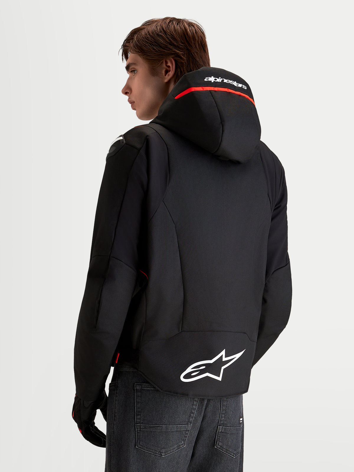 Casaco Alpinestars Zaca V 2 Waterproof, casaco de moto para homem, preto e vermelho fluo, com capuz integrado e logótipo Astar branco na bainha traseira, vista traseira num modelo