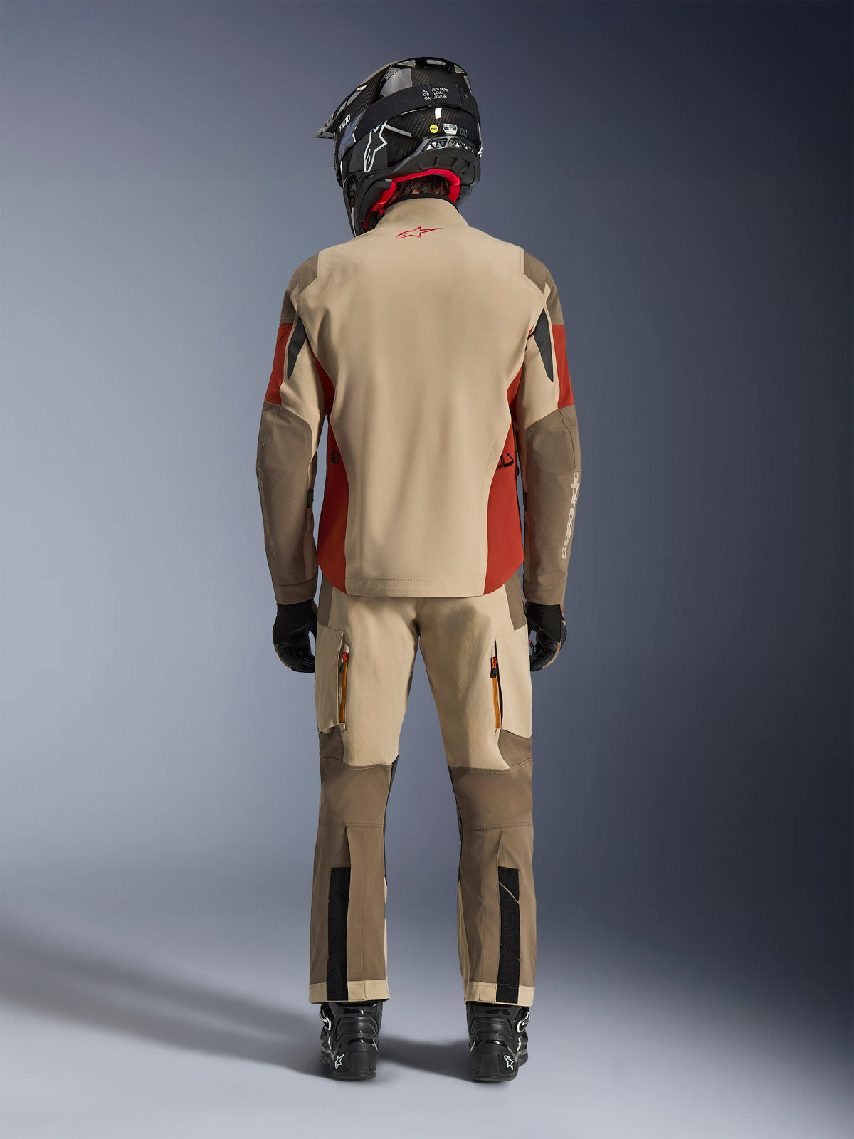 Alpinestars Maxdura Drystar®XF Laminated Armored Shell, casaco de aventura e calças a condizer, cores Aluminum Walnut e Rust Brown, vista traseira do motociclista com capacete e botas pretas, equipamento profissional de adventure-touring