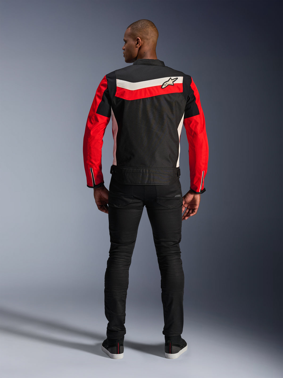Casaco Alpinestars T-Dyno WR, casaco de motociclismo em têxtil, Preto Vermelho Brilhante e Ecru, vista traseira com riscas horizontais nas costas e mangas vermelhas, ajuste de motociclista de inspiração vintage, usado com calças pretas, equipamento de condução urbana em estrada