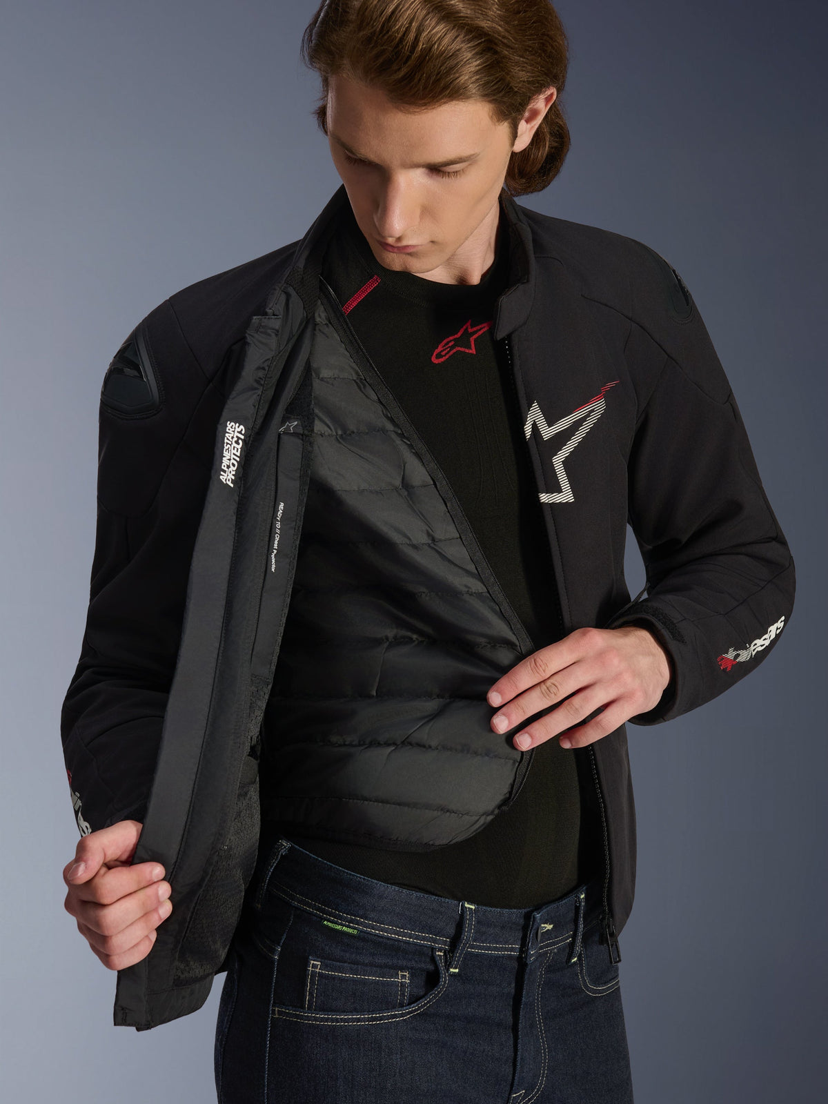 Casaco Alpinestars SMX Waterproof em preto, branco e vermelho brilhante, vestido por um homem e aberto para revelar o forro térmico amovível acolchoado, com proteções de ombros DFS Lite externas e pormenores do logótipo em branco, equipamento de motociclismo de estrada de alta performance