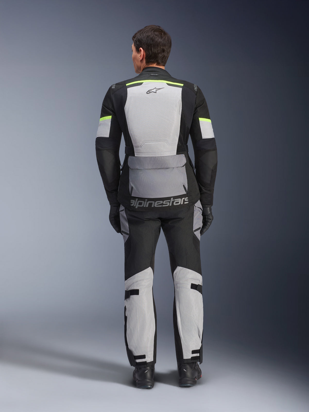 Alpinestars Andes Air Drystar® Jacket and Pants, Ice Gray Dark Gray Black adventure touring kit, rear view of rider wearing complete gear with neon yellow accents, featuring large mesh ventilation panels and Alpinestars branding.