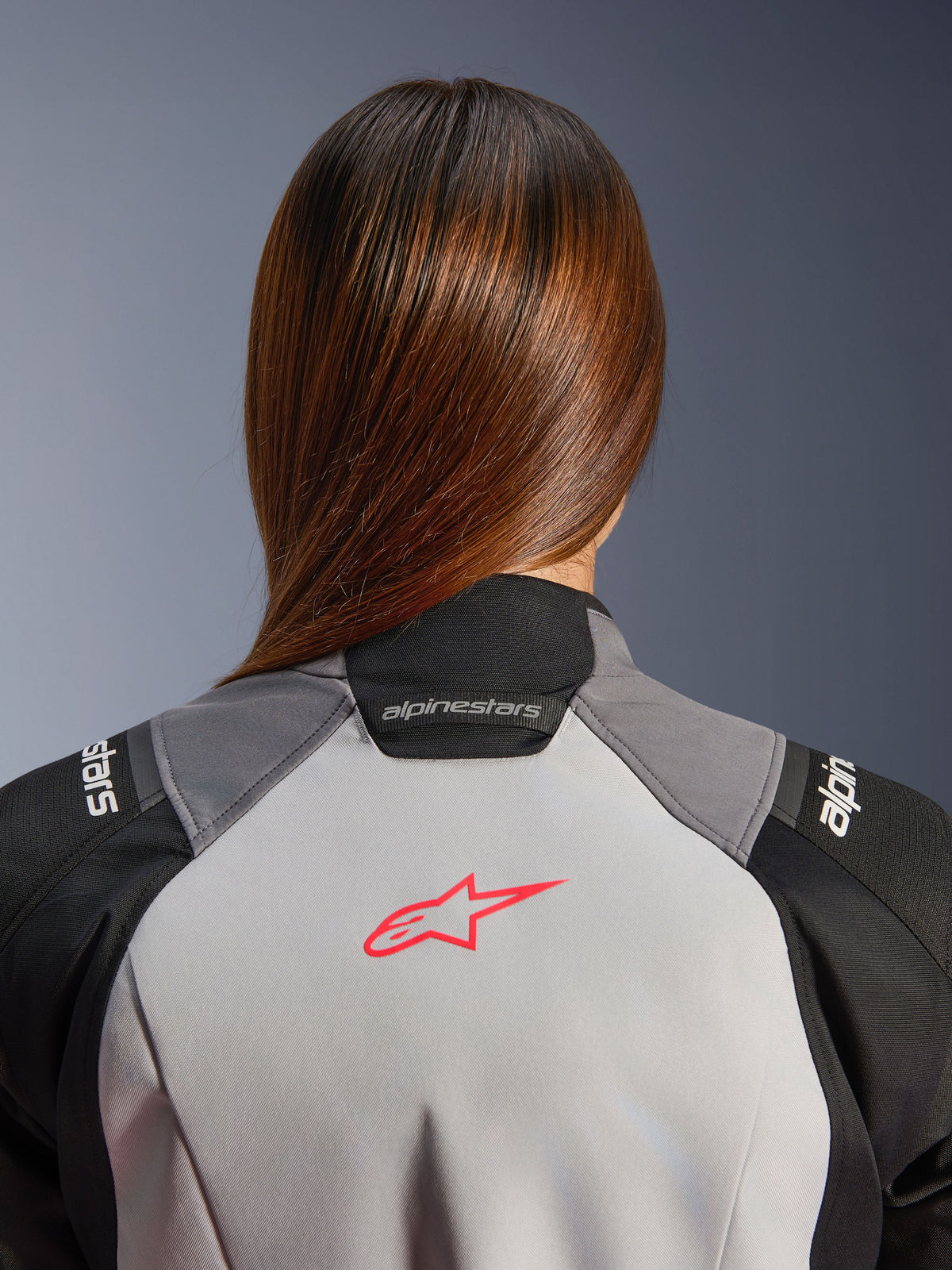 Alpinestars Stella Andes V4 Drystar, casaco de moto de aventura para mulher, impermeável, cinzento gelo e preto, pormenor do logótipo coral fluo nas costas e colarinho.
