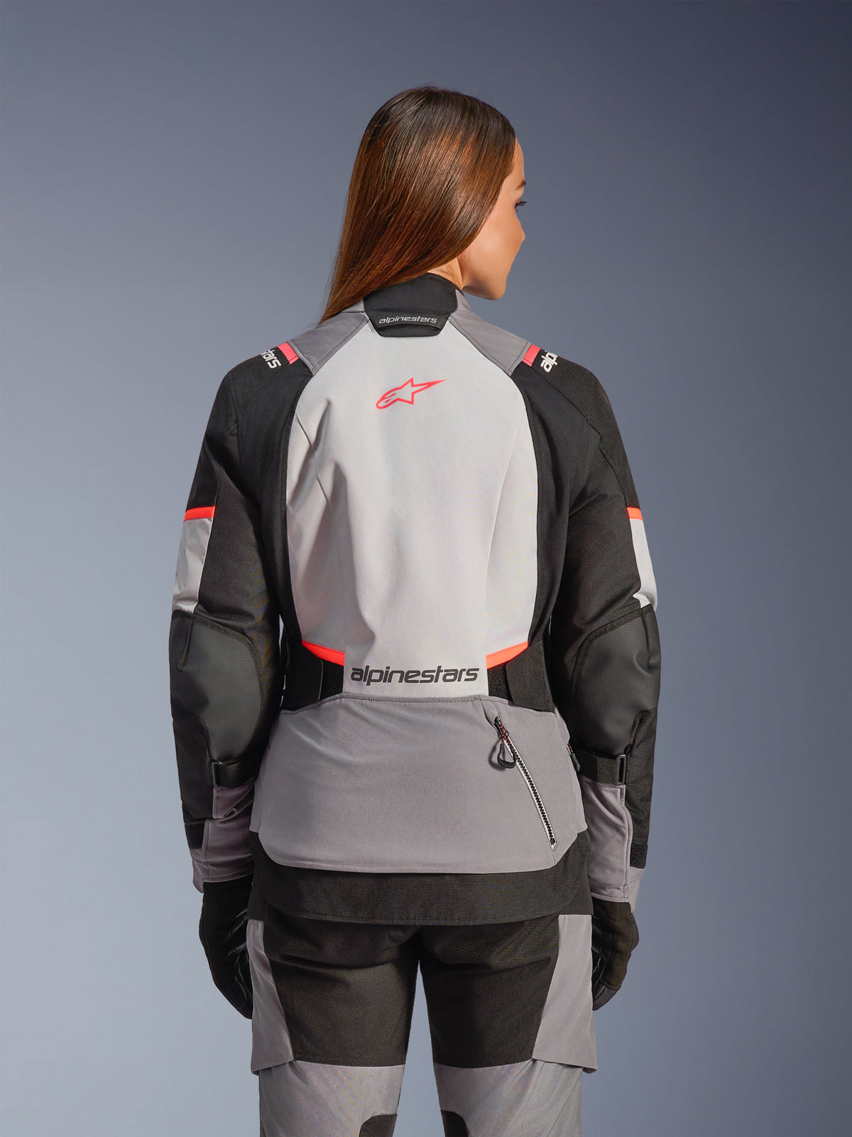 Alpinestars Stella Andes V4 Drystar®, casaco de moto de aventura para mulher, cinzento e coral, vista traseira, impermeável e respirável.