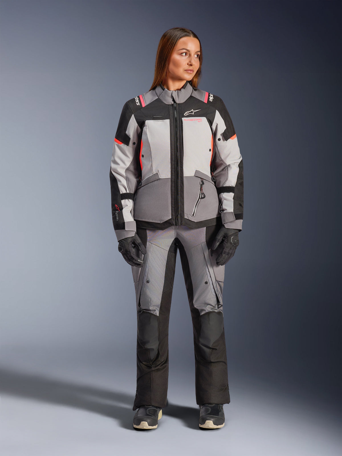 Alpinestars Stella Andes V4 Drystar, casaco de moto para mulher em cinzento e preto com detalhes coral, estilo aventura.