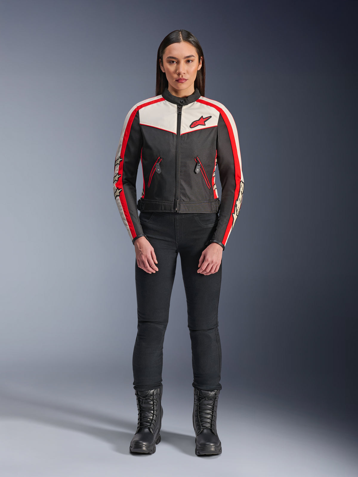 Casaco Alpinestars Stella T-Dyno WR, casaco de motociclismo têxtil para mulher, preto, cru e vermelho vivo, usado por modelo com calças e botas pretas, com design de inspiração vintage, logótipo Alpinestars vermelho e painéis contrastantes.