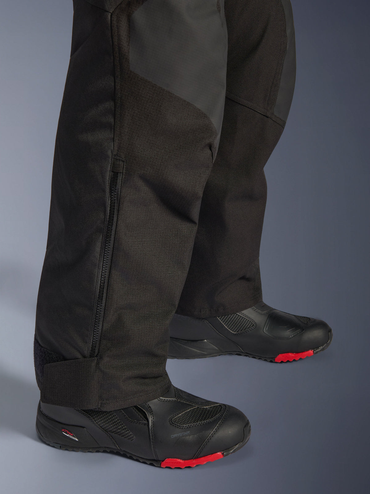 Alpinestars Andes V4 Drystar® Pants - Short, Black, close-up of lower leg detail showing textile construction, vertical zipper for ventilation, and adjustable ankle cuffs, worn with black motorcycle boots