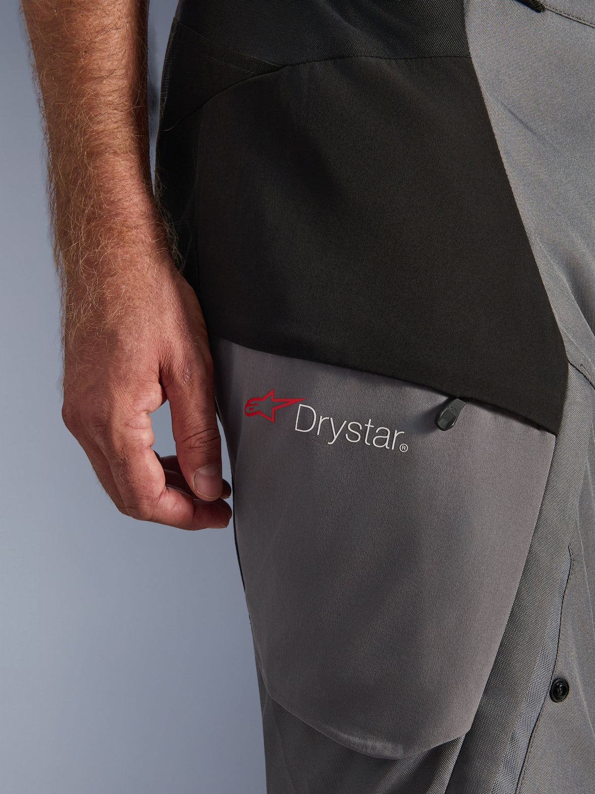 Alpinestars Andes V4 Drystar® Pants, Black Dark Gray, close-up of thigh detail with red star logo and Drystar® branding, durable textile construction with zippered pocket, adventure riding apparel