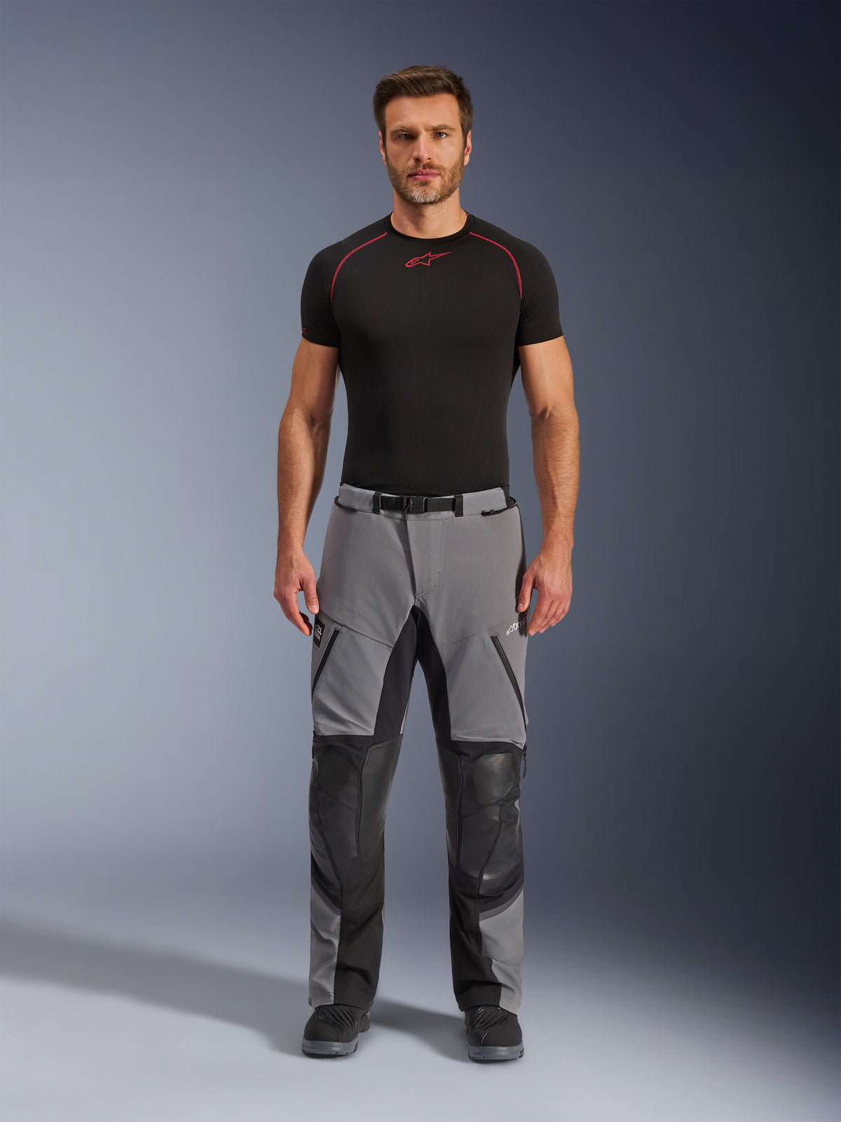 Alpinestars Andes Pro Drystar® XF Pants, Adventure Motorcycle Pants, Dark Gray and Black, front view worn by a model with a black base layer, featuring reinforced knee panels and waterproof zippered pockets.