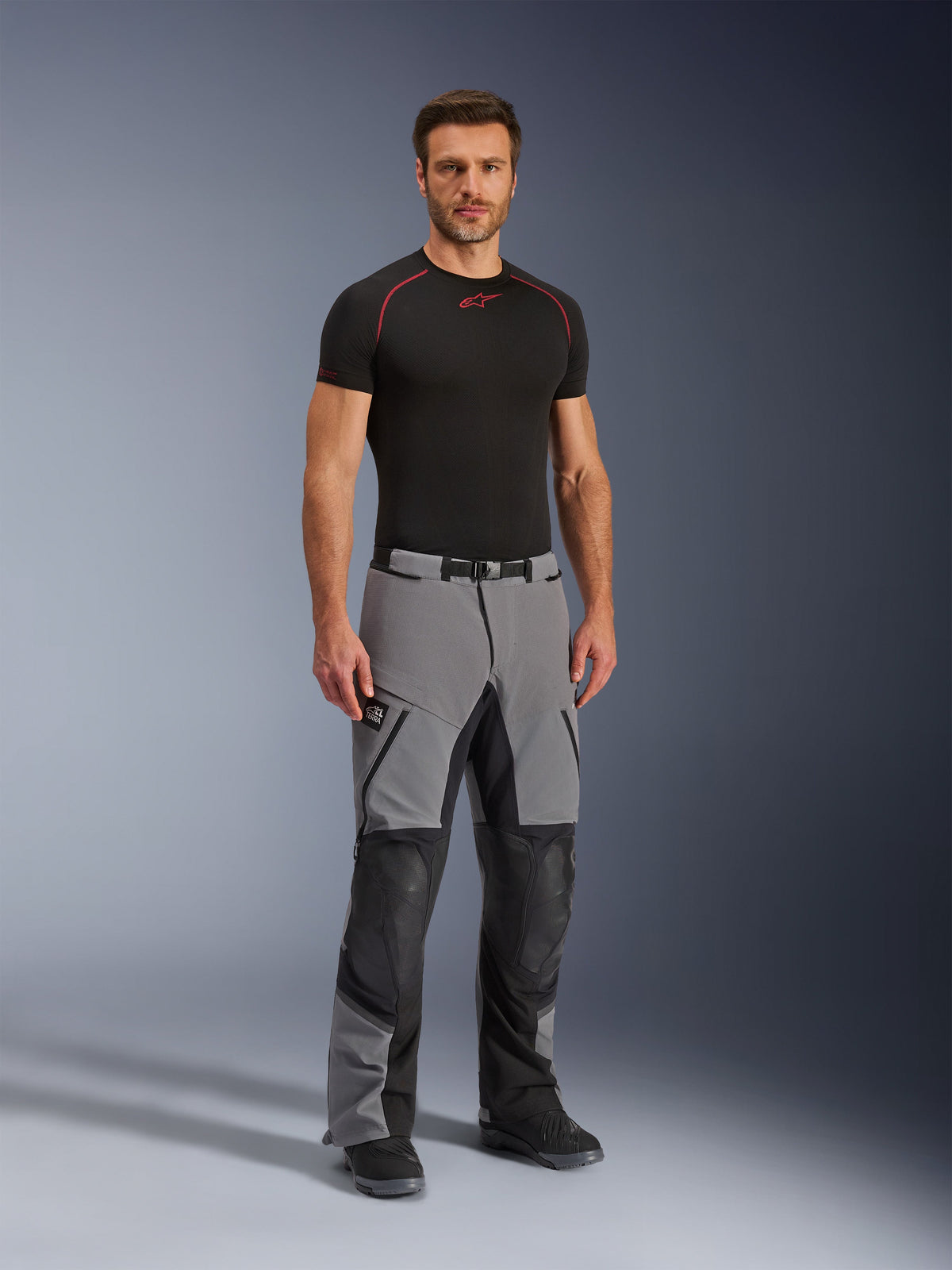 Alpinestars Andes Pro Drystar® XF Pants, Motorcycle Adventure Pants, Dark Gray and Black, worn by a model with a black technical base layer, featuring multi-panel construction with waterproof zippers and reinforced zones for adventure riding.