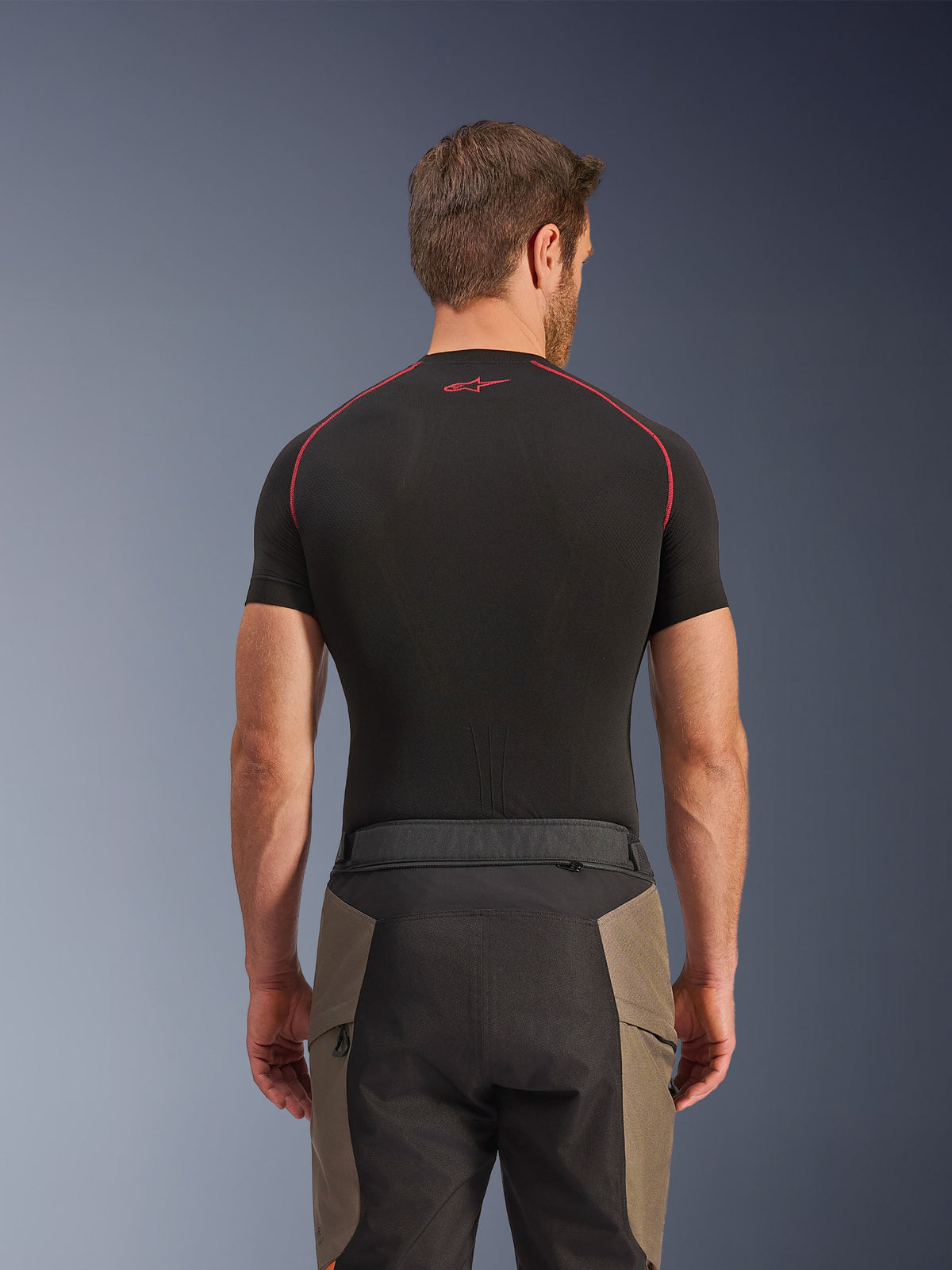 Alpinestars Cusco Drystar® Pants, calças de aventura, Walnut Black, vista traseira com detalhes da cintura e design em blocos de cor, usadas com uma camada de base preta de manga curta com costuras vermelhas e logótipo