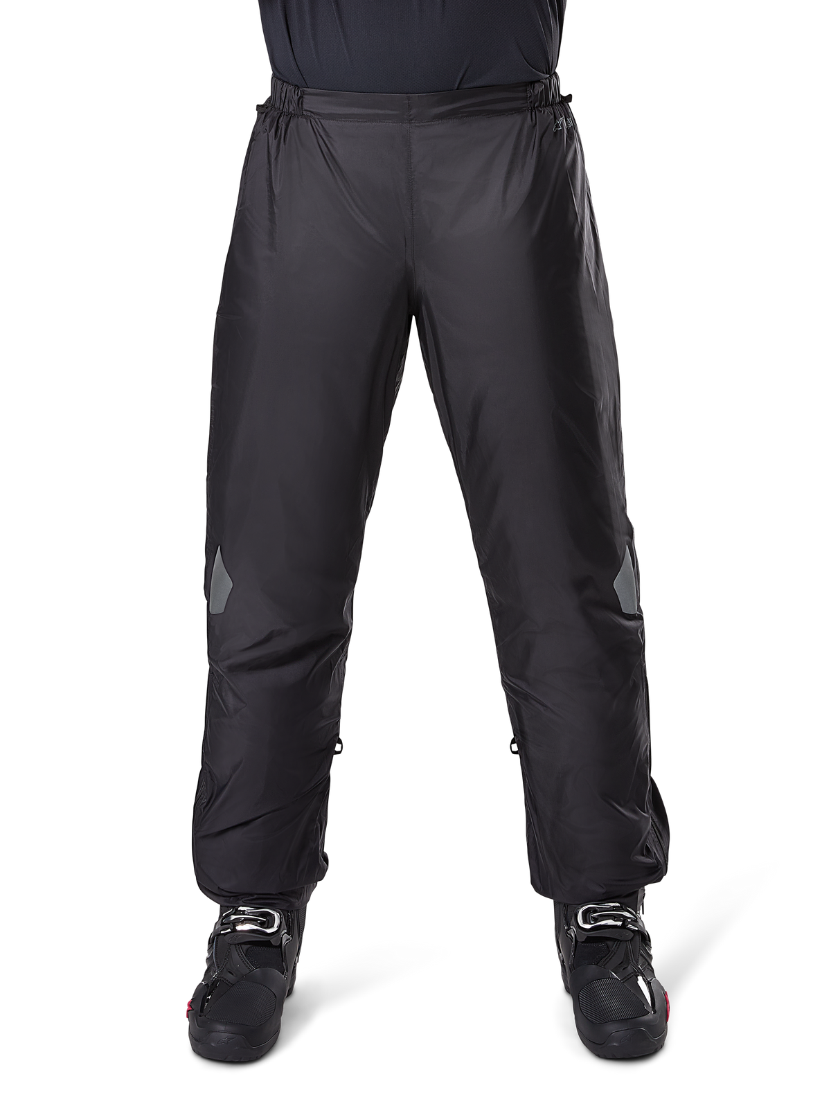 Alpinestars Bogota Pro Drystar 3 Seasons Pants, calças de motociclismo impermeáveis, pretas, tecido técnico leve com detalhes refletores nos joelhos, usadas como sobrecalças com botas de motociclismo pretas, concebidas para proteção contra as intempéries em viagens de aventura