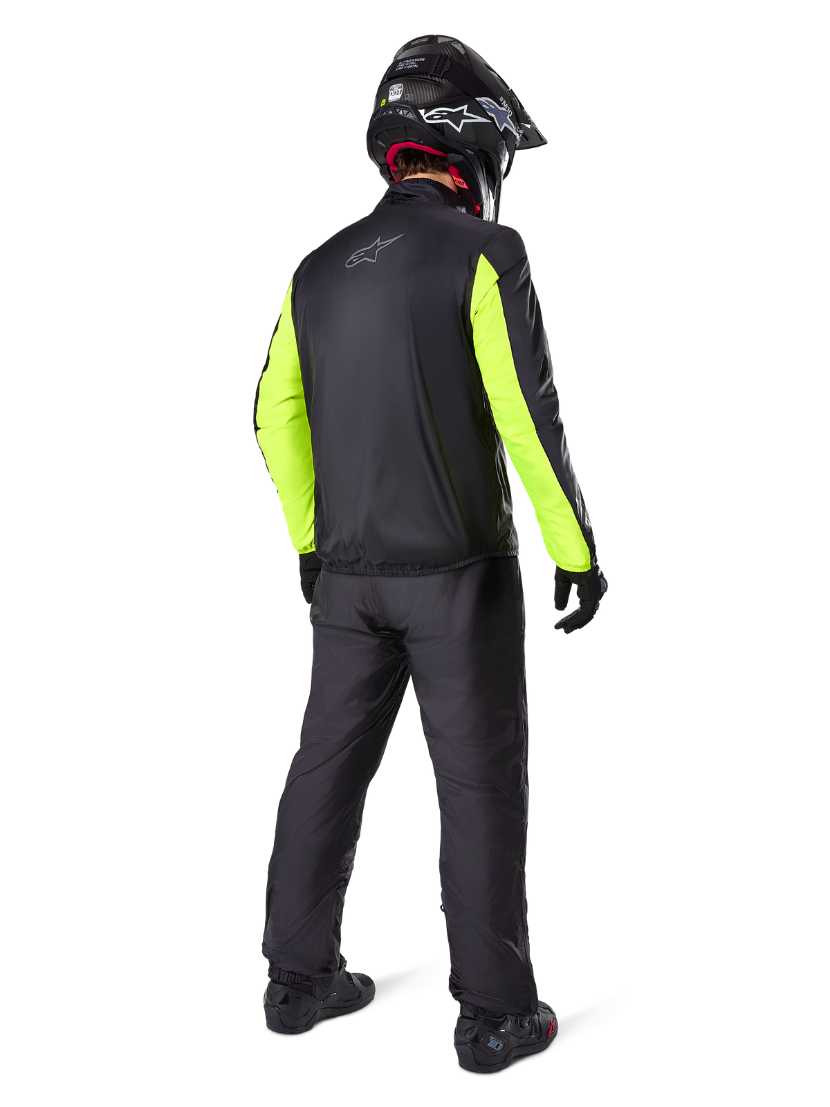 Motociclista visto de costas a usar as calças Alpinestars Bogotá Pro Drystar® 3 Seasons em preto, combinadas com um casaco preto com mangas amarelo fluorescente, capacete de aventura preto e botas, equipamento completo de adventure touring