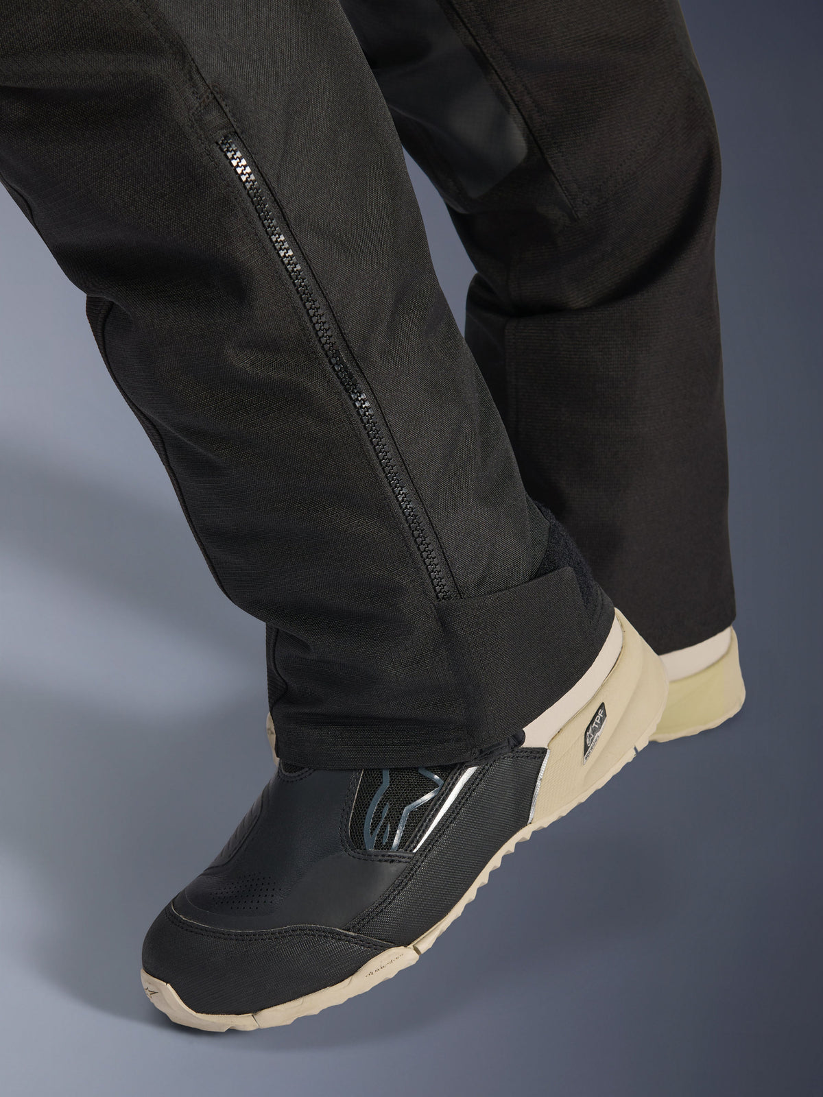 Alpinestars Stella Andes V4 Drystar® Pants, Black, close-up of lower leg featuring a side zipper for boot adjustment, durable textile material, worn with black and tan motorcycle boots, adventure-ready functional design