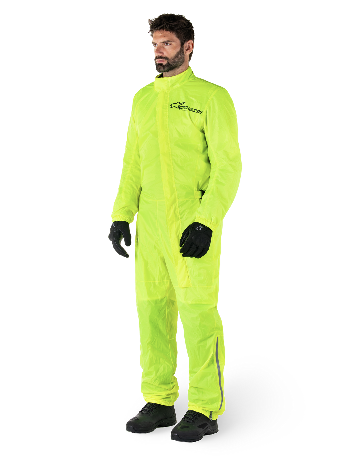 Alpinestars Hurricane Rain V2 Suit, fato de motociclismo impermeável de uma peça, Amarelo Fluo, usado com luvas e botas pretas, com logótipo preto da Alpinestars no peito e detalhes refletores nas pernas