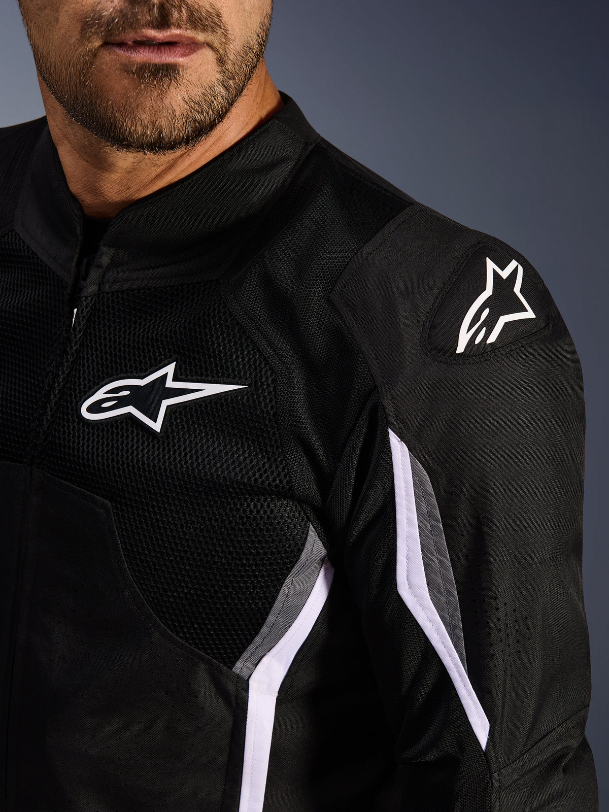 Casaco Alpinestars AST V3 Air, casaco de motociclismo têxtil, preto, cinzento escuro e branco, grande plano com painéis de malha, logótipo Alpinestars branco no peito e no ombro, e deslizadores de ombro externos DFS GP Lite Evo