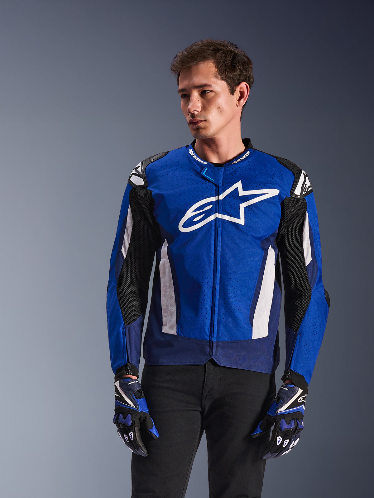 Alpinestars T-GP Air Jacket, Sport Textile Motorcycle Jacket, Bright Blue and Navy with White accents, featuring large star logo on chest, mesh ventilation panels, worn by model with matching gloves and black pants