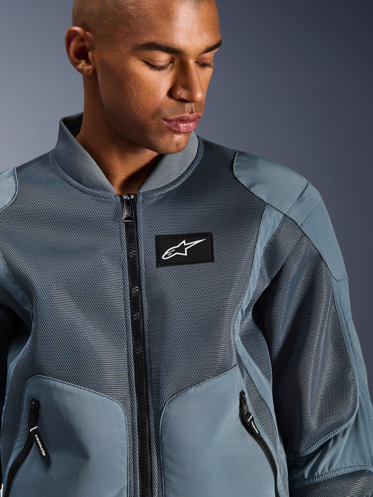 Alpinestars Flight Air Jacket, cinzento Storm, casaco de motociclismo urbano, com painéis de malha 3D e gola canelada estilo bomber, emblema preto com o logótipo Alpinestars no peito, tecido técnico respirável para deslocações em tempo quente