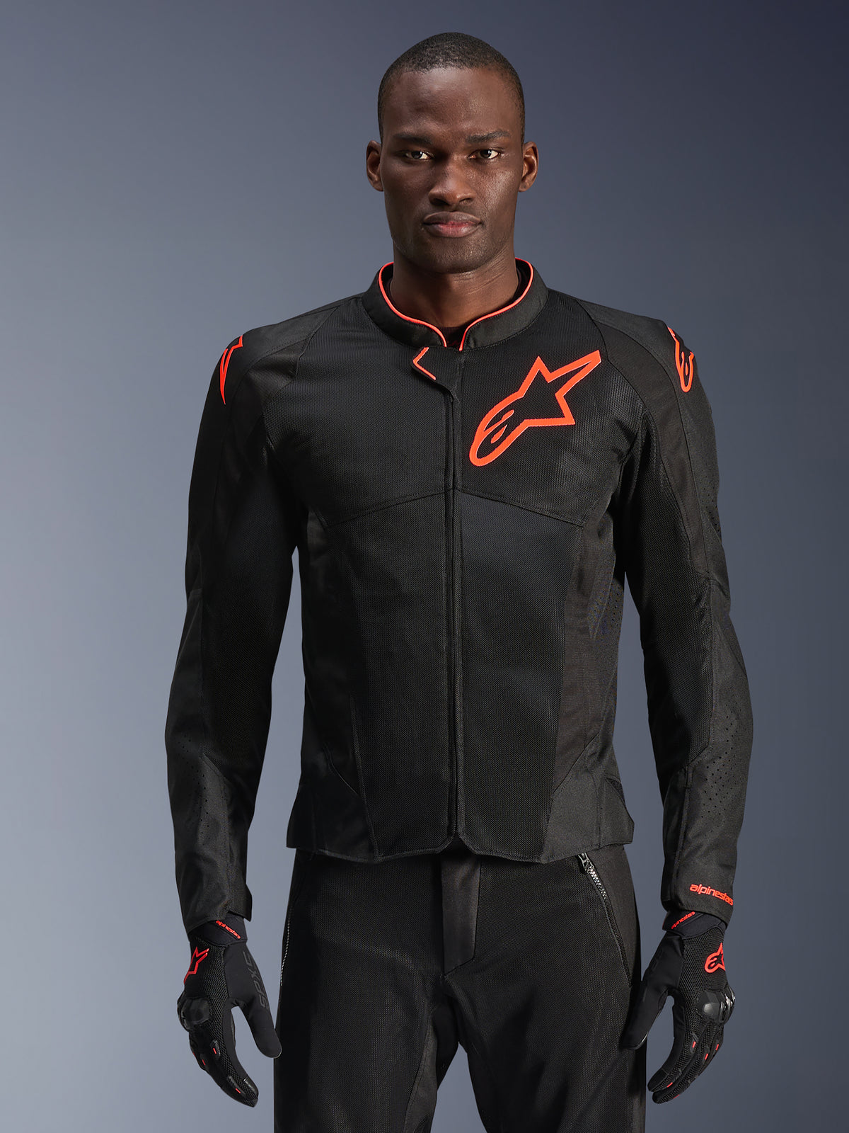 Casaco Alpinestars Viper Air V4, casaco de motociclismo preto e vermelho fluo, construção em malha ventilada com logótipo de estrela vermelho proeminente, usado por modelo com luvas a condizer, design de performance desportiva