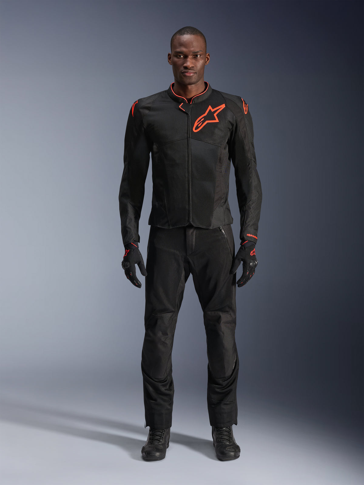 Casaco Alpinestars Viper Air V4 em Preto Vermelho Fluo, vestido por um modelo com calças e luvas pretas a condizer, com painéis de malha para fluxo de ar e o logótipo Alpinestars vermelho proeminente no peito, equipamento desportivo de estrada para motociclismo