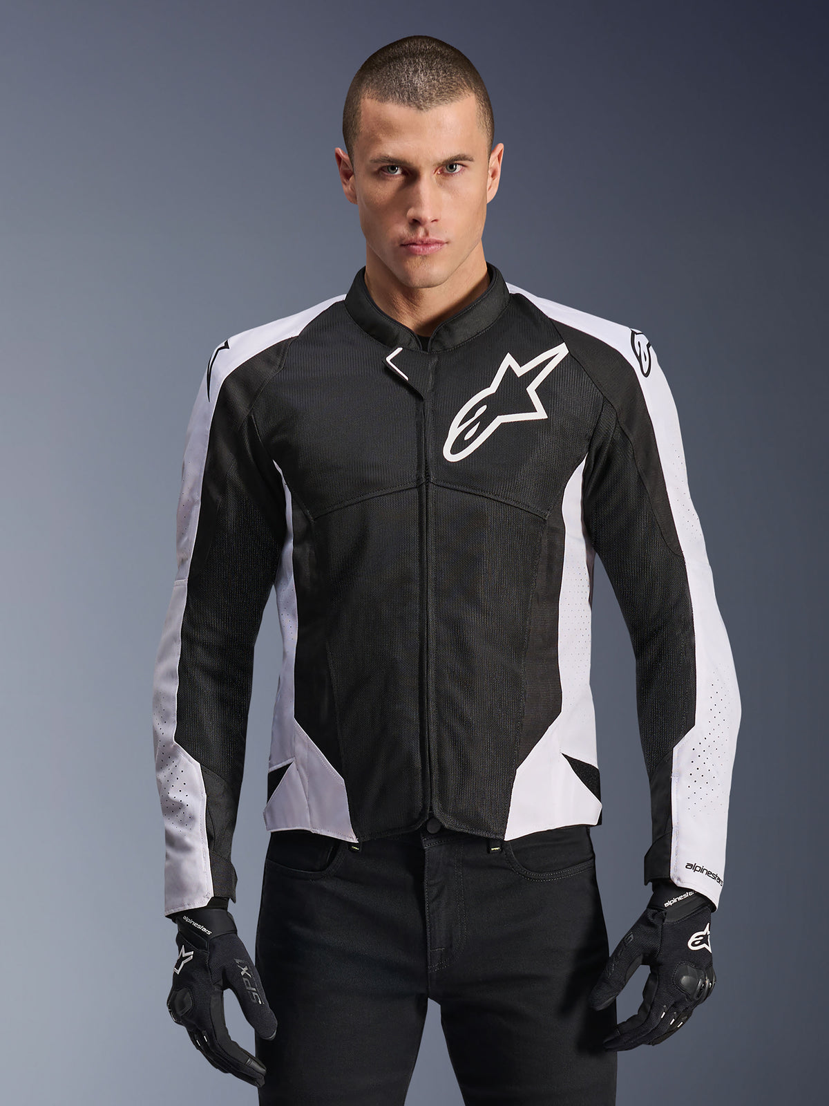 Casaco Alpinestars Viper Air V4, casaco de motociclismo, preto e branco, usado por um motociclista, construção em malha técnica e têxtil com painéis brancos nos ombros, logótipo de estrela proeminente no peito, design de performance desportiva, combinado com luvas de motociclismo pretas