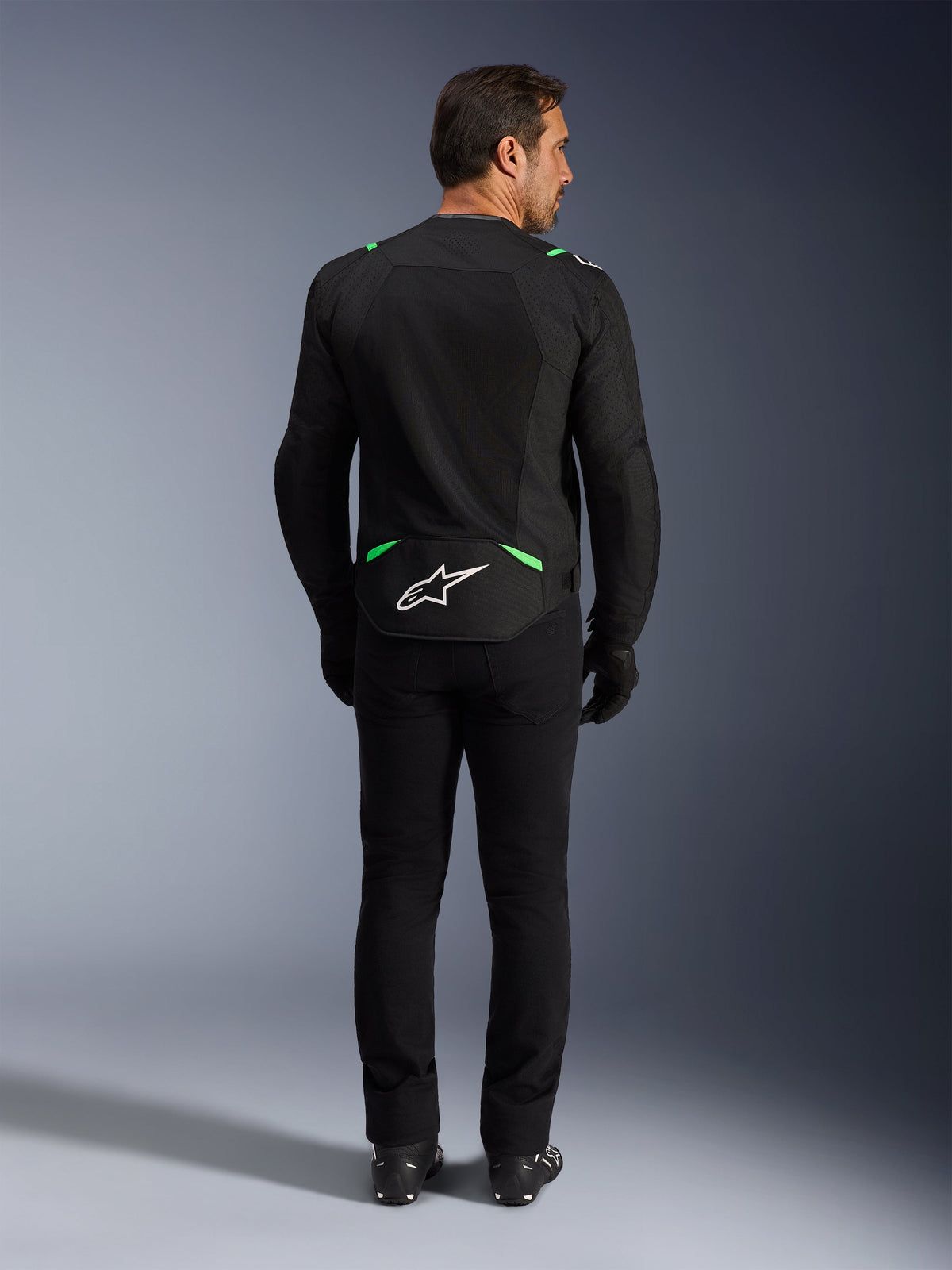 Casaco Alpinestars T-SPS Air V2, casaco de motociclismo, preto e verde fluo, vista traseira com logótipo branco na parte inferior das costas, usado com calças e botas pretas a condizer, design em malha ventilada para condução desportiva