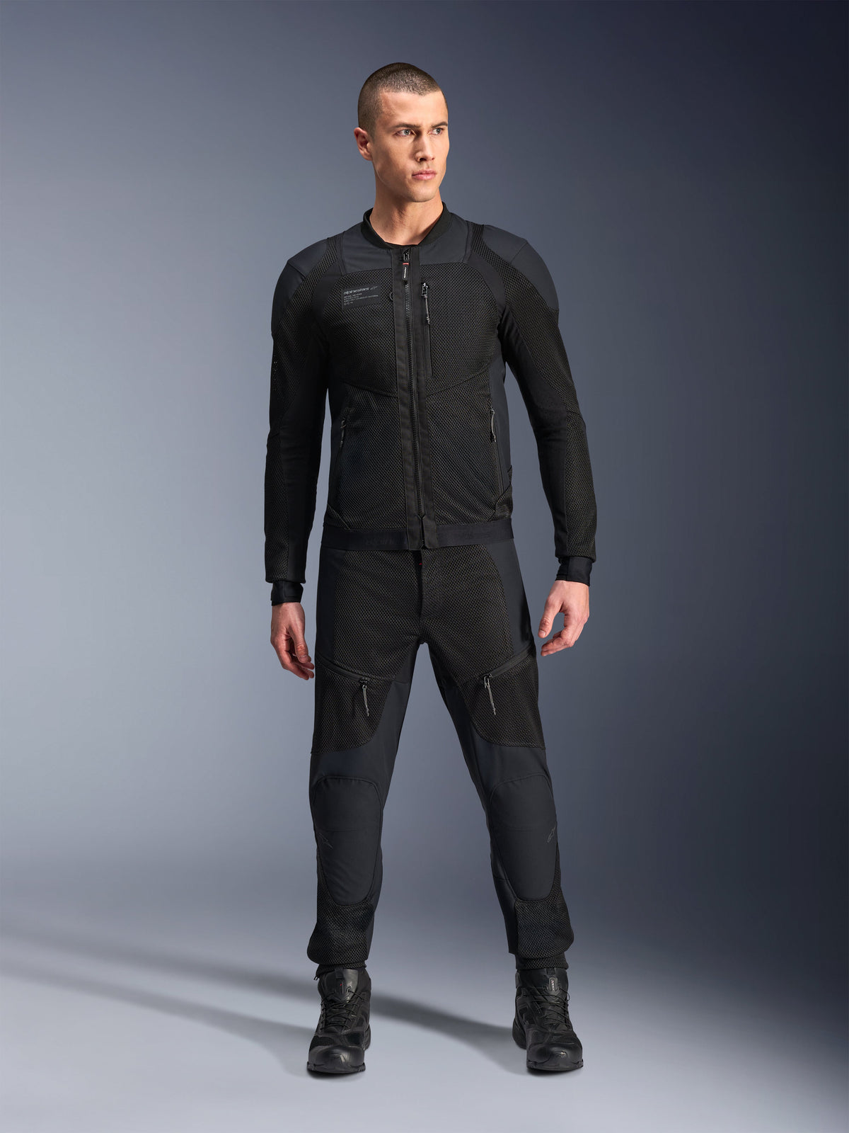 Alpinestars Troop-Air Pro Jacket, casaco de motociclismo técnico blindado preto, com painéis de malha e fechos frontais, usado com calças pretas a condizer e botas de condução, equipamento urbano premium