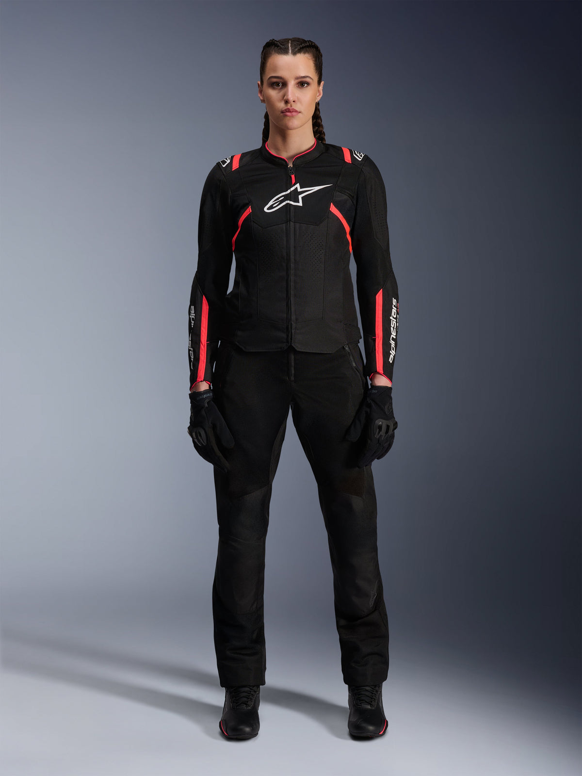 Casaco Alpinestars Stella T-SPS Air v2, casaco de motociclismo para mulher, preto e cor-de-rosa Diva, vista frontal, logótipo branco no peito, painéis de ventilação em malha, usado com calças e luvas pretas, equipamento de condução urbana elegante